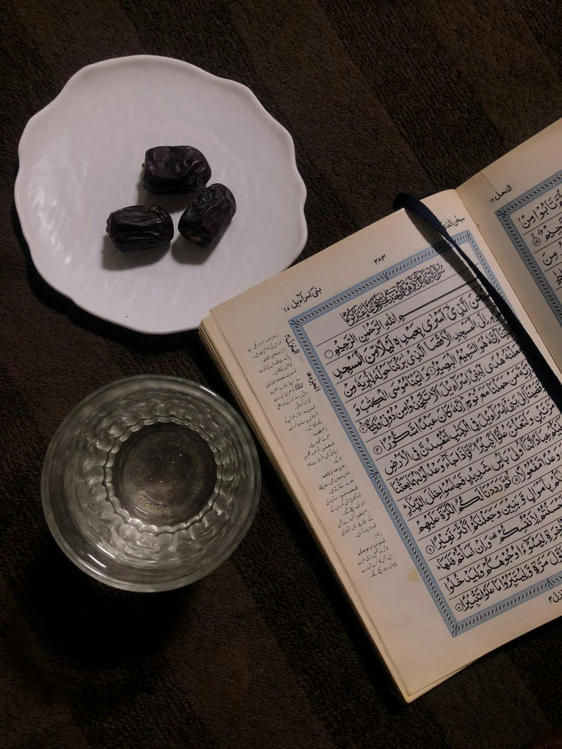 Gratis Åben Koran med dadler og vand, der symboliserer Ramadans spirituelle og fastetraditioner. Lagerfoto