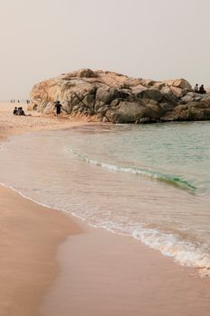 Peaceful beach with gentle waves and rocky outcrop, perfect for relaxation.