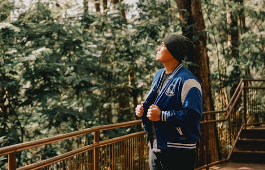 Man with knitted hat and blue jacket enjoying a peaceful forest walk on a sunny day.