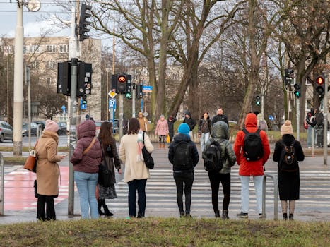 Pedestrians in winter attire waiting to cross a busy street.