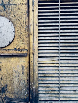 Close-up of a rusty metal vent with peeling paint, displaying weathered industrial textures.