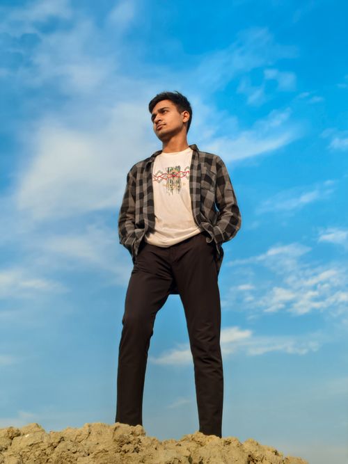 Free Young man stands confidently on mound against a striking blue sky. Stock Photo
