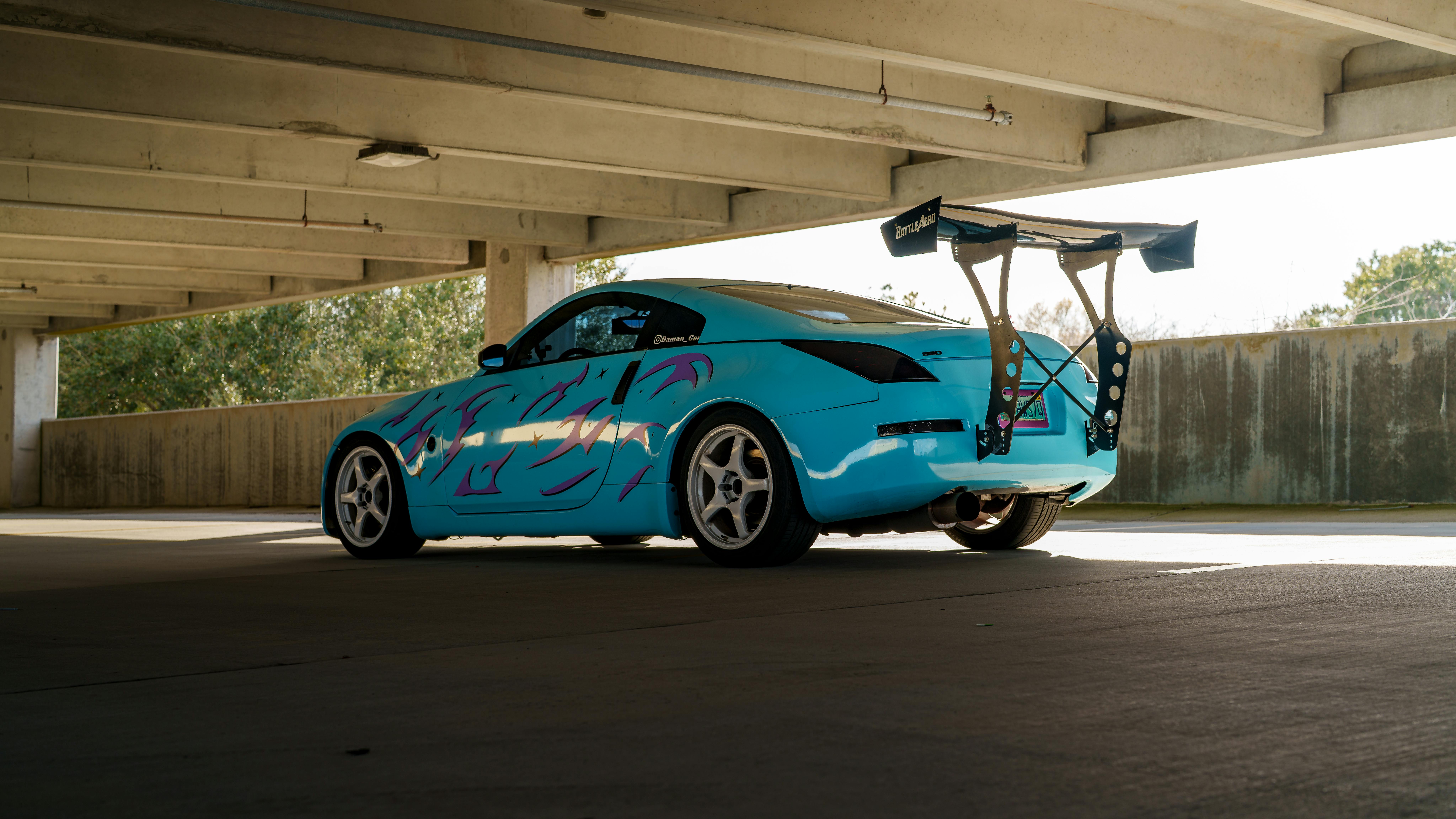 Stylish custom blue car with purple graphics parked in a garage, showcasing a sporty design.