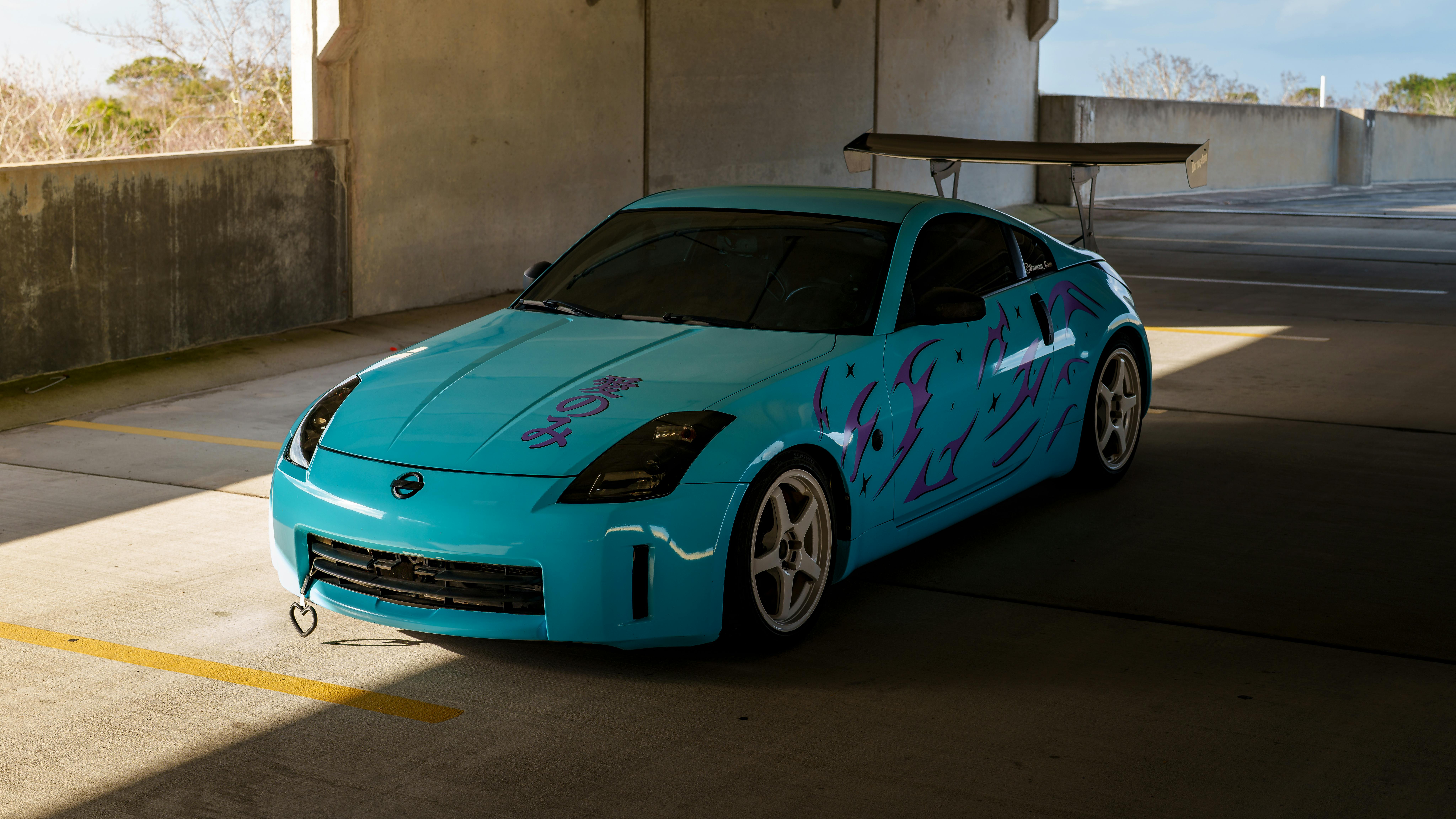 Gratis Sebuah mobil sport berwarna biru terang dengan grafis kustom yang menarik perhatian terparkir di garasi, memamerkan desainnya yang ramping. Foto Stok