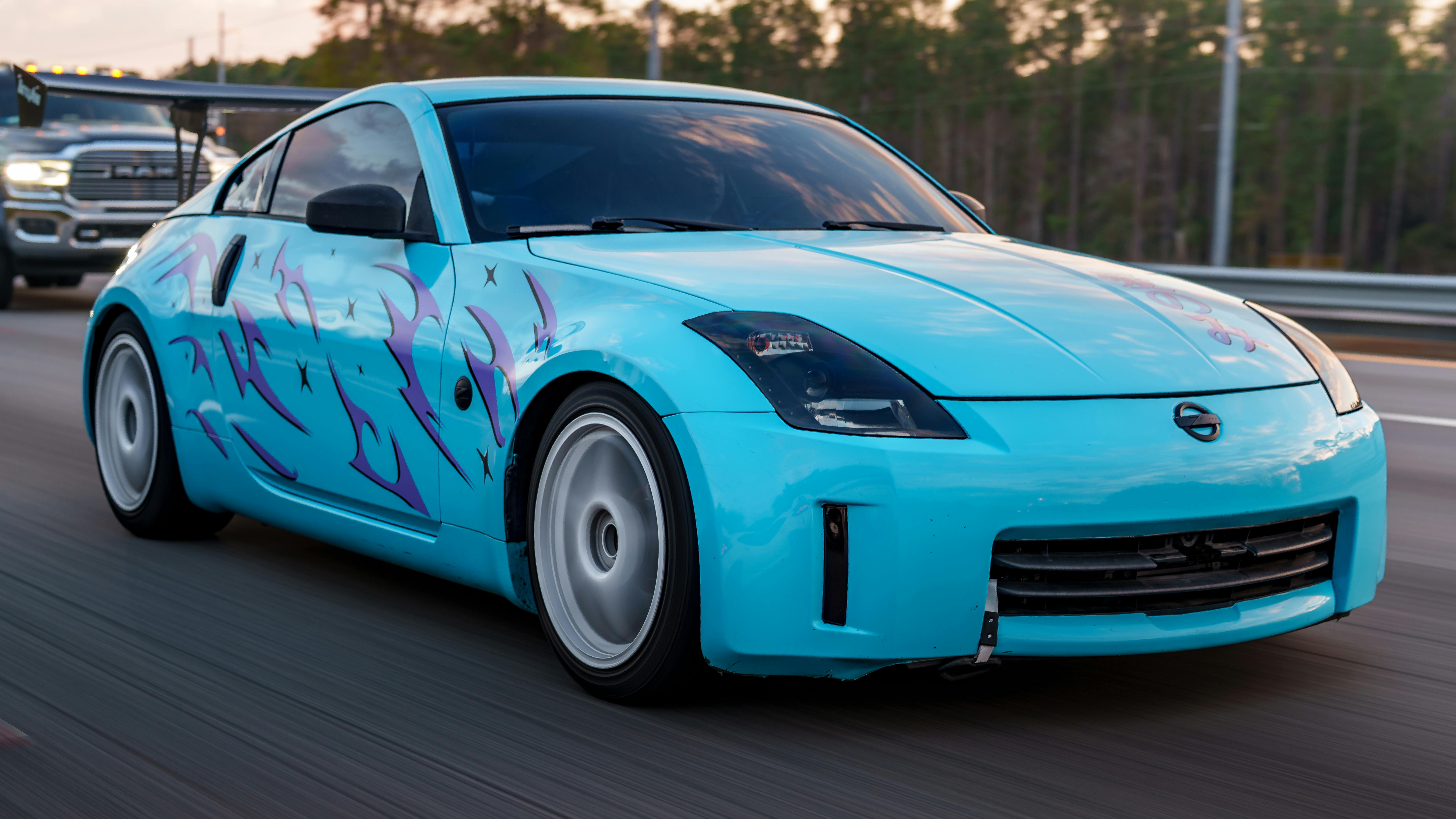 Stylish blue sports car with custom flames speeding down the highway.