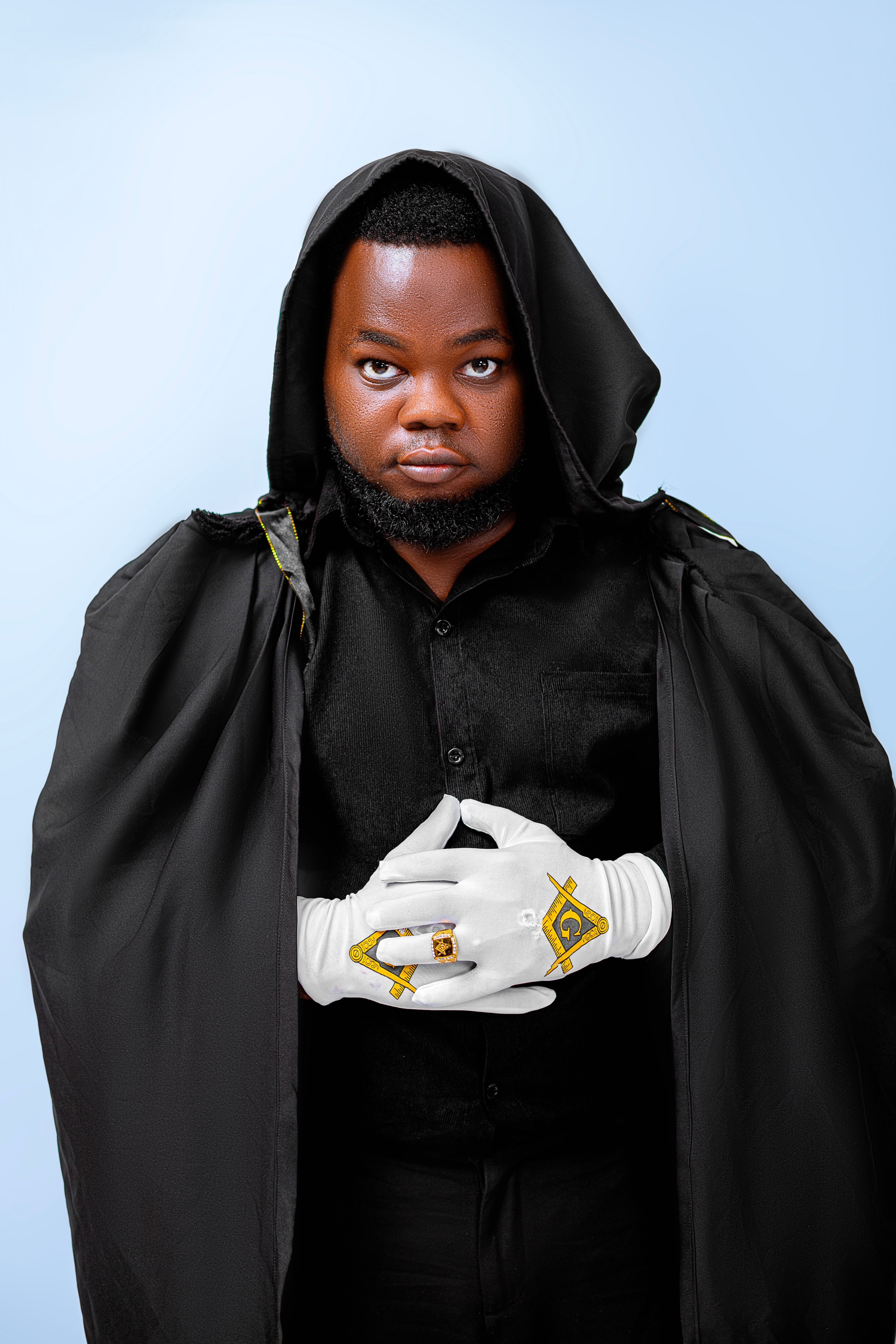 A man in Masonic clothing with a hooded cloak and white gloves, posing formally.