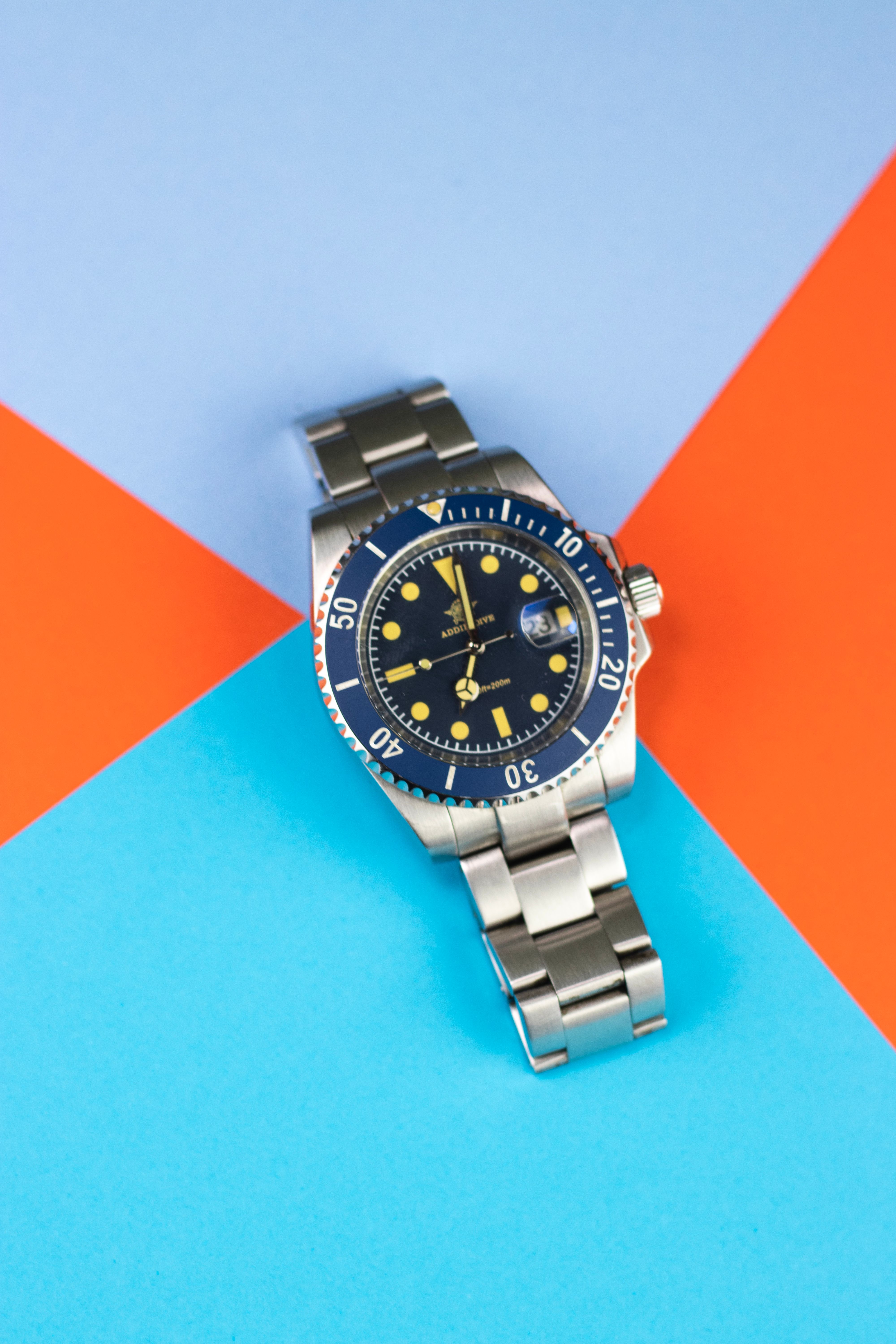 Elegant analog wristwatch with a blue face on a vibrant geometric background showcasing modern fashion design.