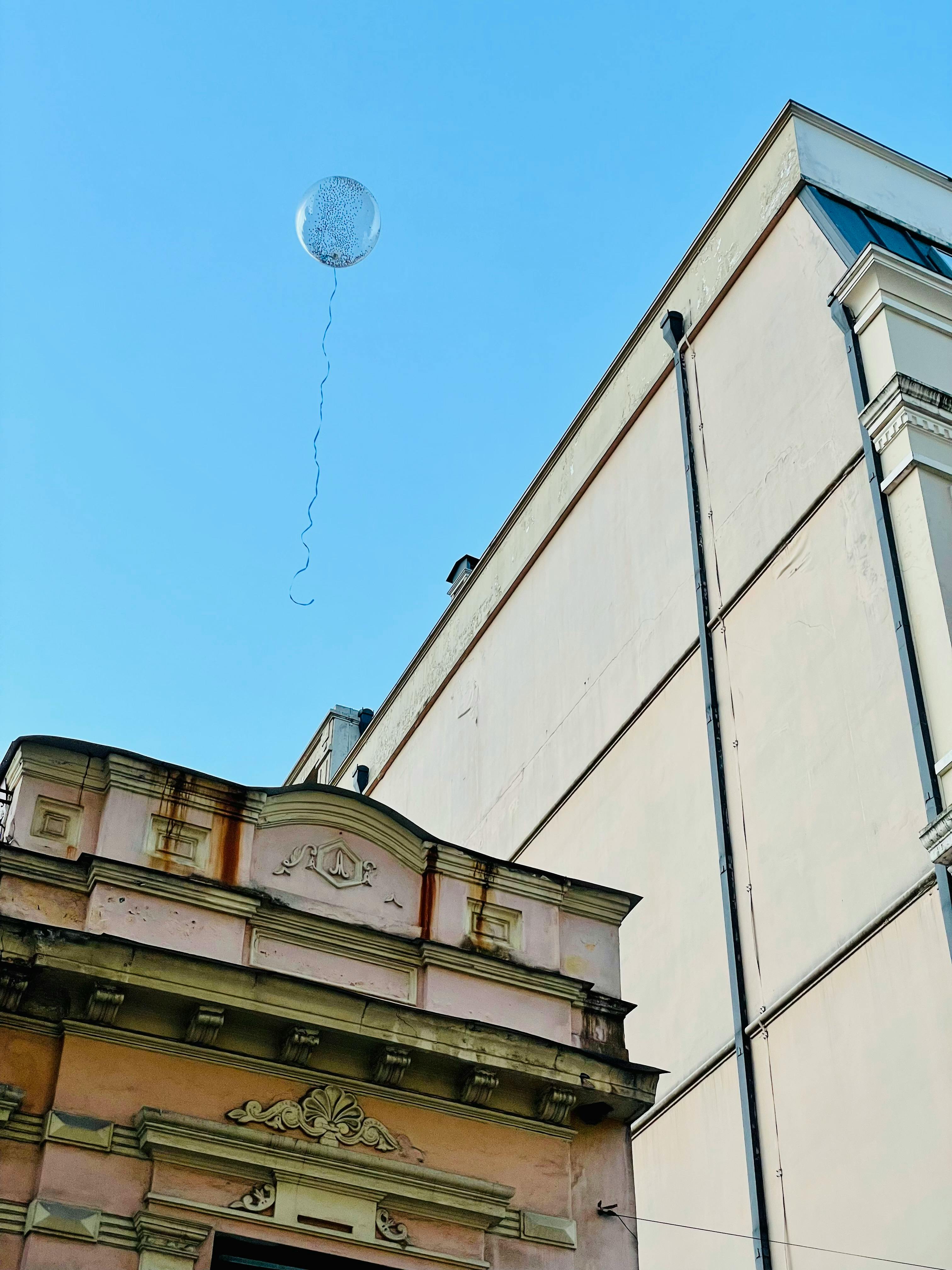 無料 明るい青空の下、ジョージアのバトゥミにある歴史的な建物の正面の上に、一個の風船が浮かんでいる。 写真素材