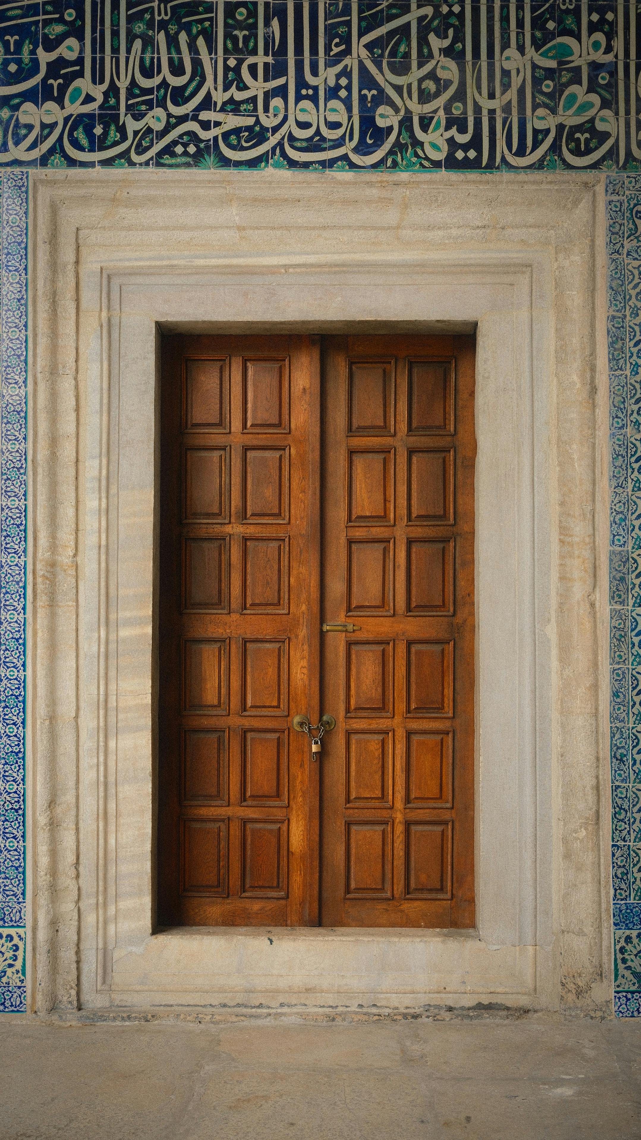 無料 複雑なイスラムのカリグラフィーとタイル模様に囲まれた伝統的な木製のドア。 写真素材