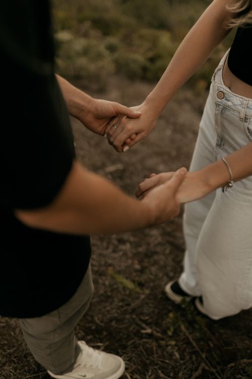 Free A young couple holding hands in an outdoor setting, symbolizing love and connection. Stock Photo
