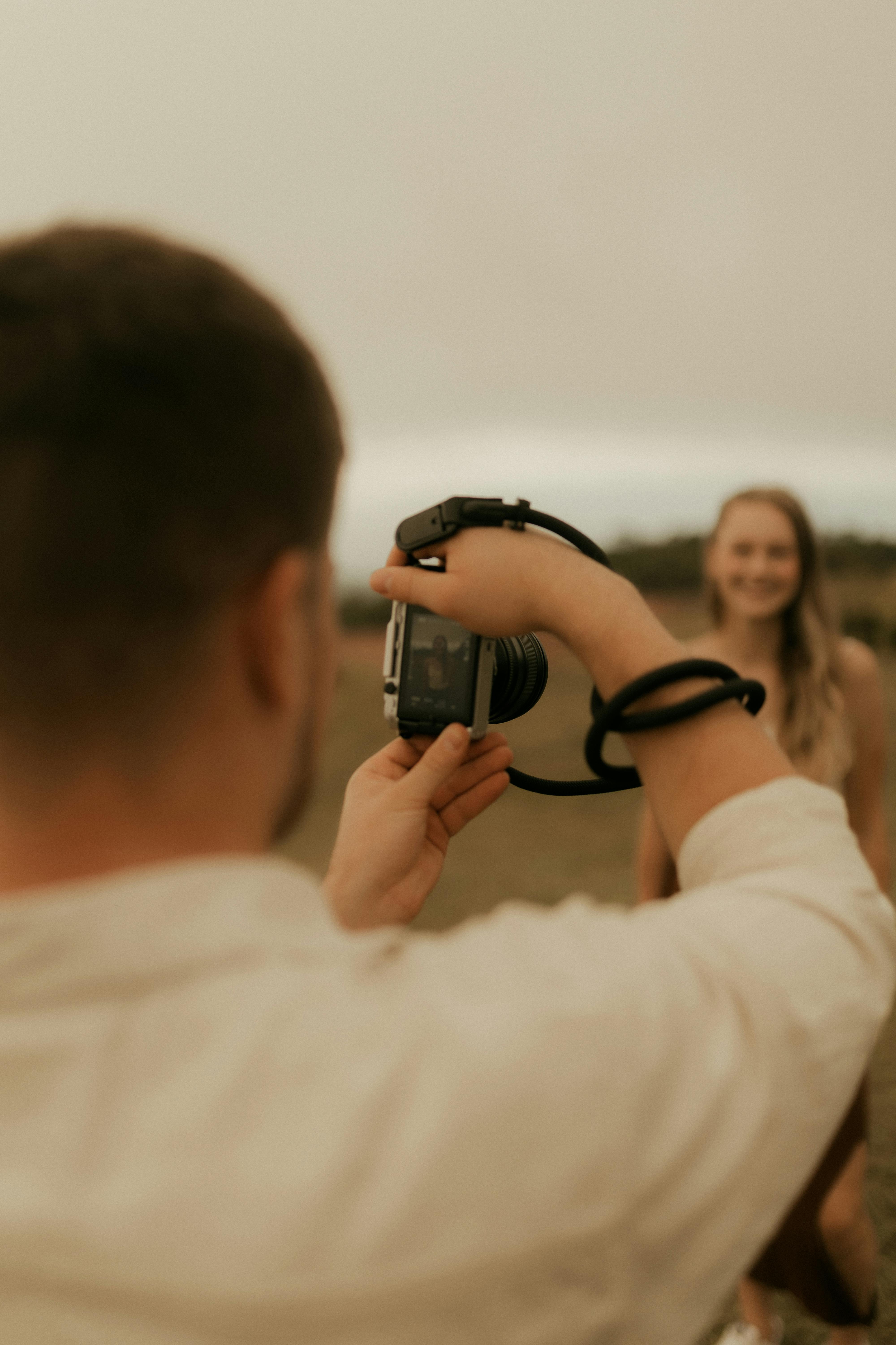 Free A photographer takes a portrait of a smiling woman during sunset in an open field. Stock Photo
