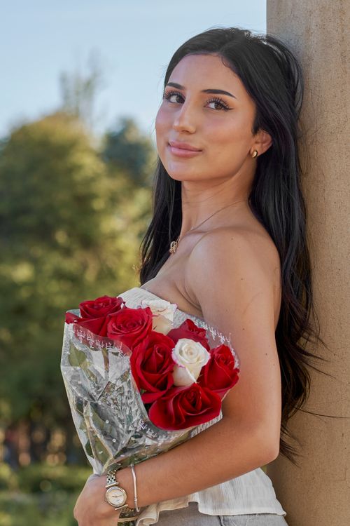 Free Charming young woman holding red and white roses outdoors in Montevideo. Stock Photo