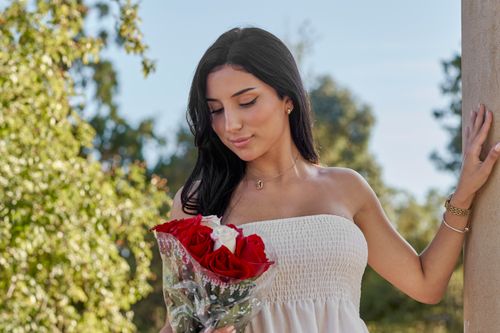 Free A young woman enjoys a sunny day holding a bouquet of red roses in Montevideo, Uruguay. Stock Photo