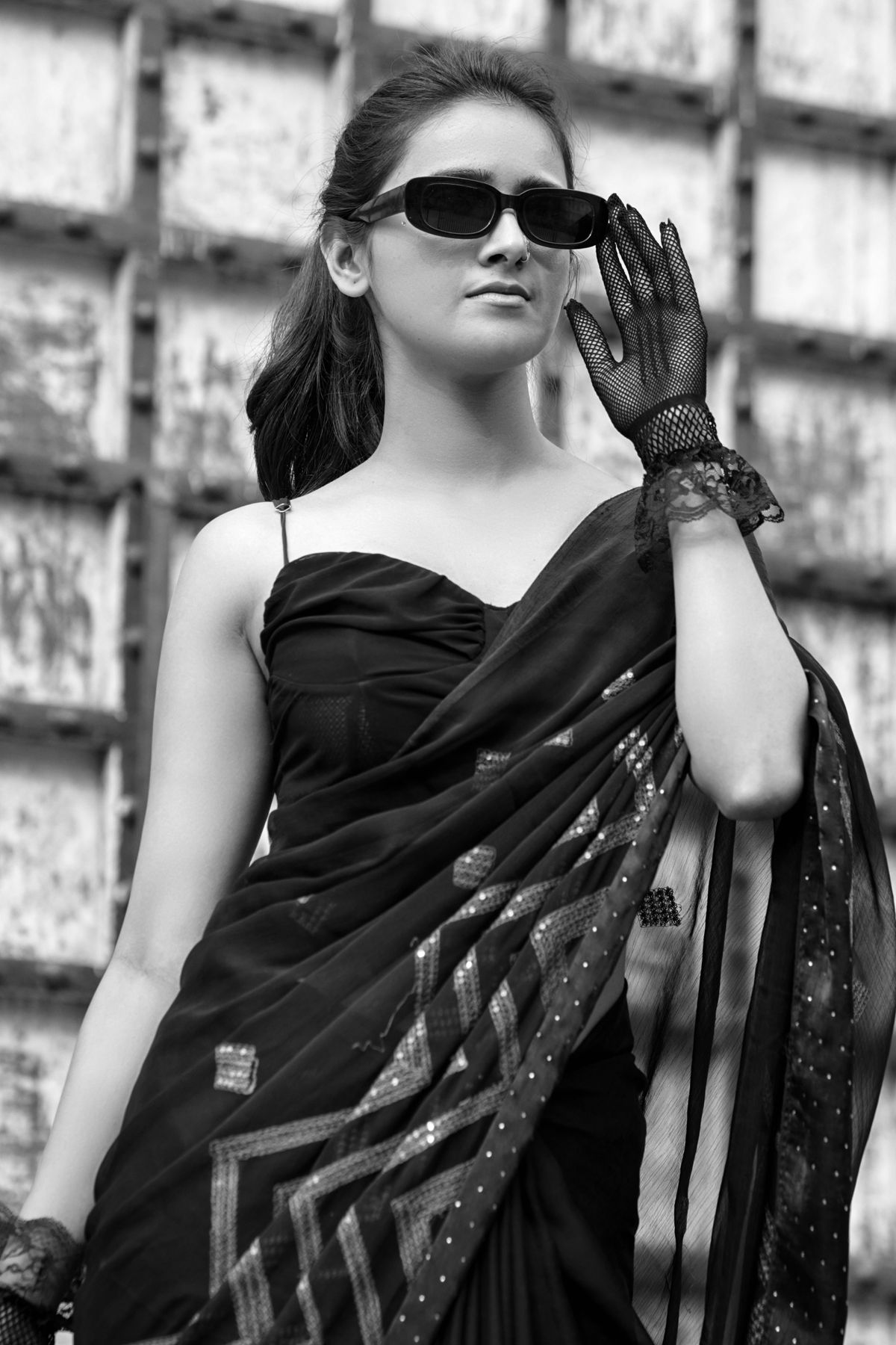 Black and white portrait of a woman in a black saree and sunglasses