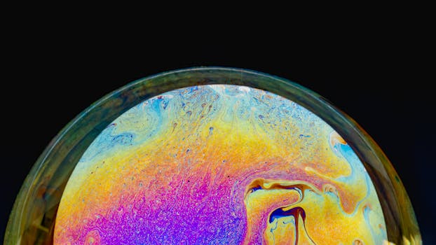 Macro shot of a colorful soap bubble displaying an iridescent spectrum against a black background.