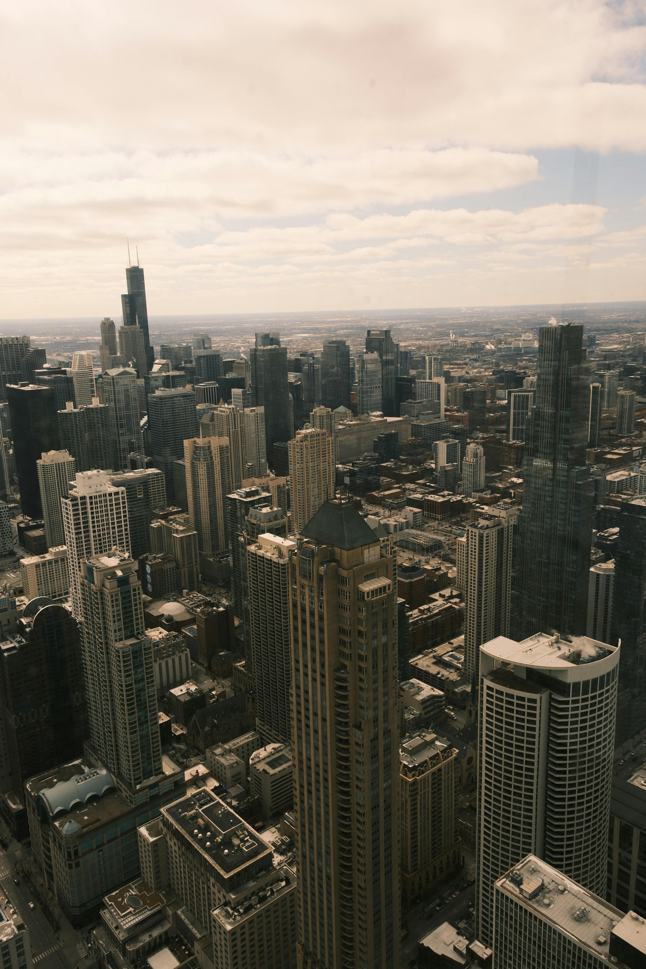 無料 曇り空の下の象徴的な高層ビルを特徴とするシカゴのダウンタウンのスカイラインの素晴らしい空中写真。 写真素材