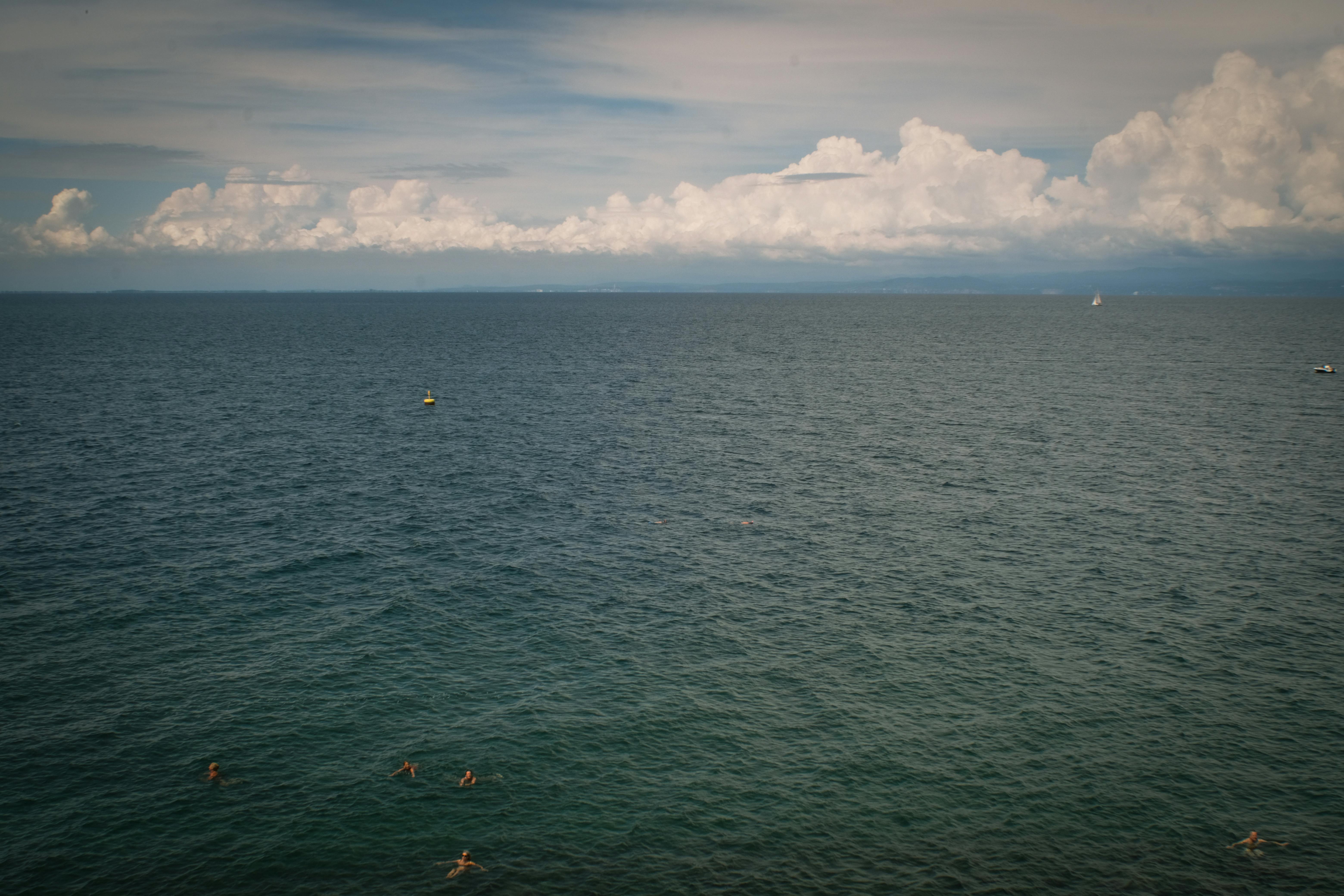Gratis Awan melayang di atas Laut Adriatik bersama para perenang di pantai Slovinsko yang indah. Foto Stok