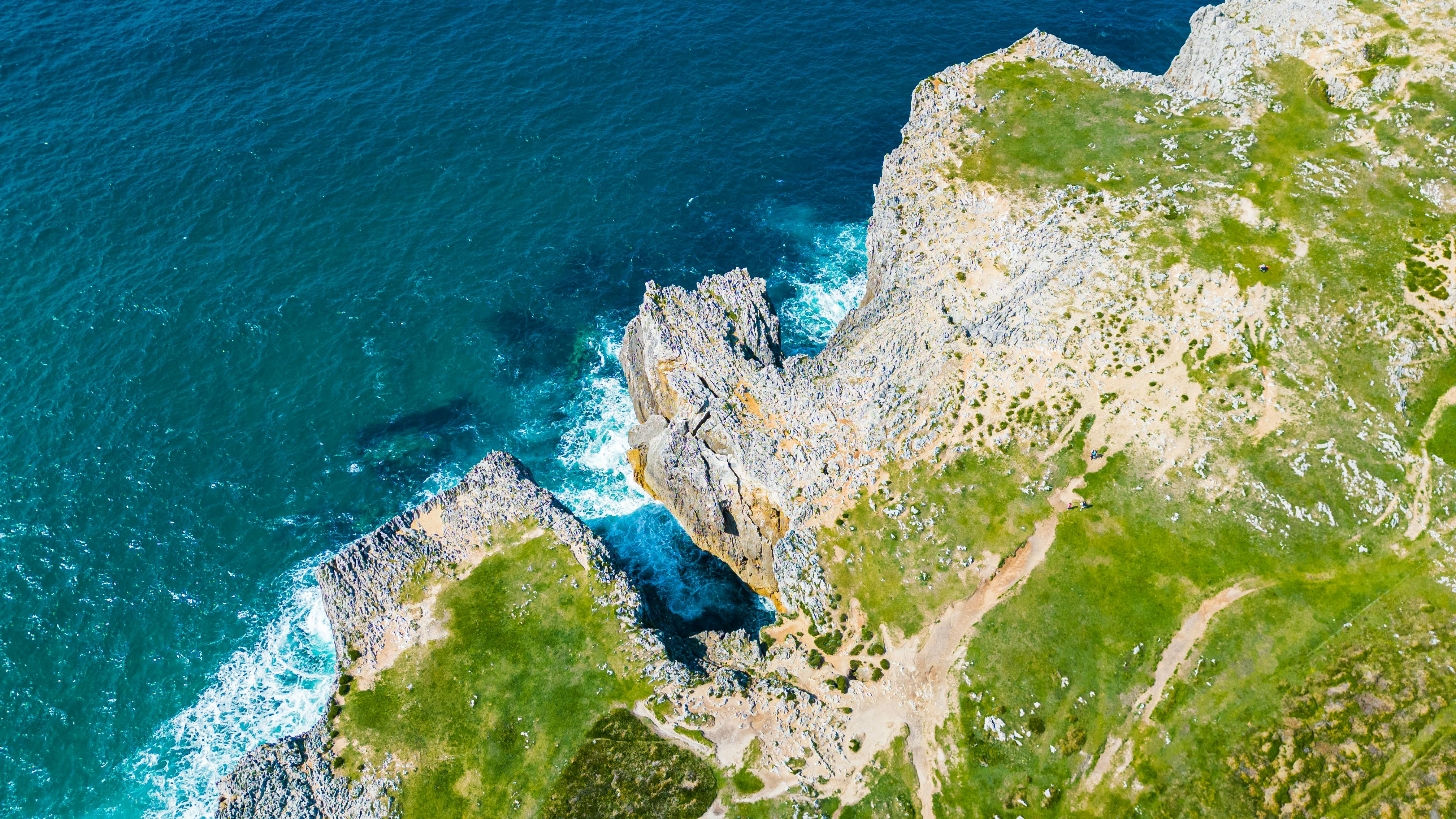 Gratis Foto udara menakjubkan yang menangkap tebing-tebing terjal dan perairan biru kehijauan di garis pantai Galicia, Spanyol. Foto Stok