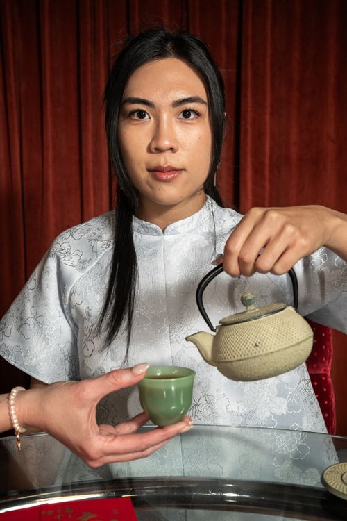Free An Asian woman pouring tea from a ceramic teapot into a cup, showcasing cultural tradition in Chicago. Stock Photo