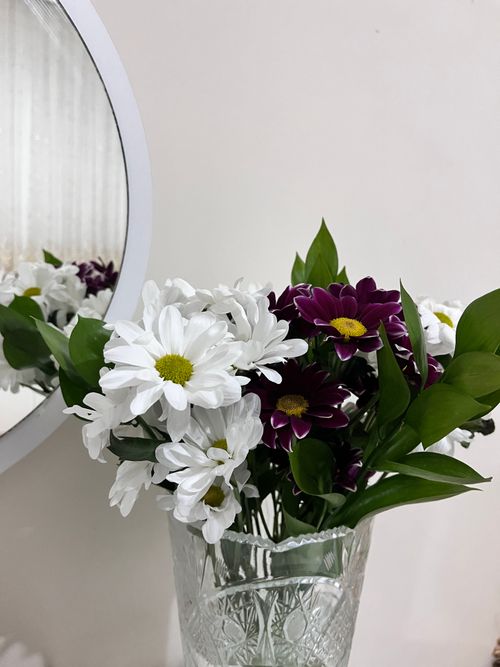 Free A crystal vase with white and purple daisies reflecting in a mirror. Stock Photo