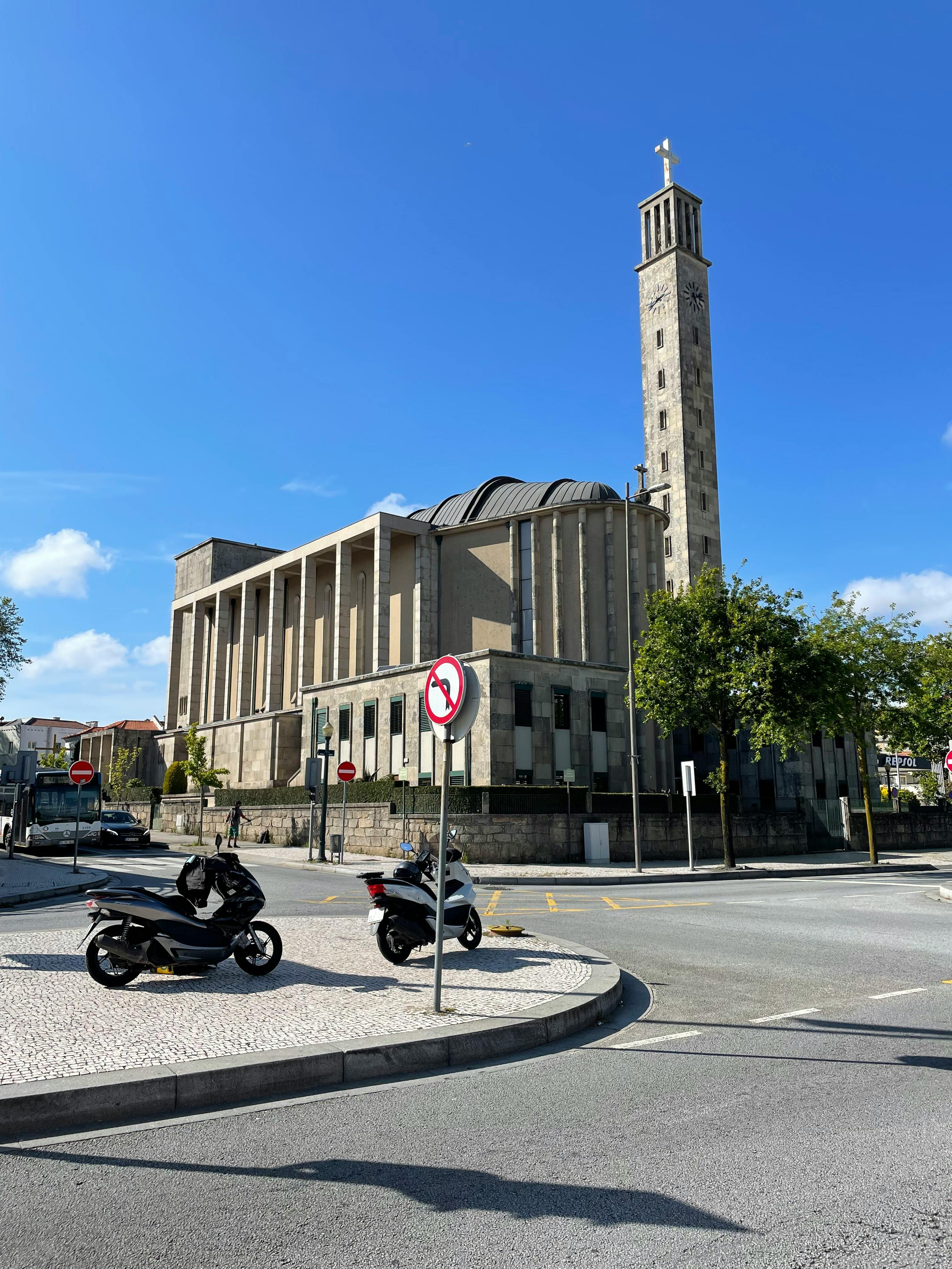 Gratis Pemandangan indah gereja ikonik Porto dengan sepeda motor yang terparkir dan langit biru cerah. Foto Stok