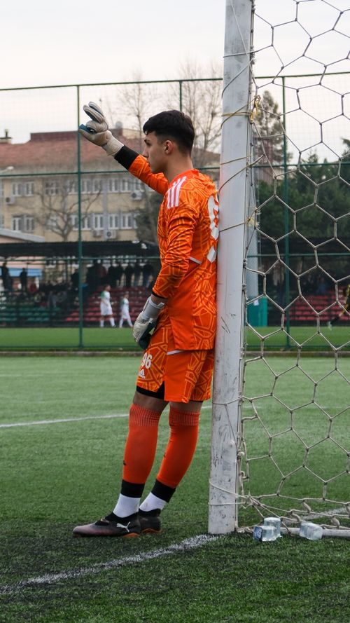 Free Soccer goalkeeper in vivid orange uniform stands by the goal on a field. Stock Photo