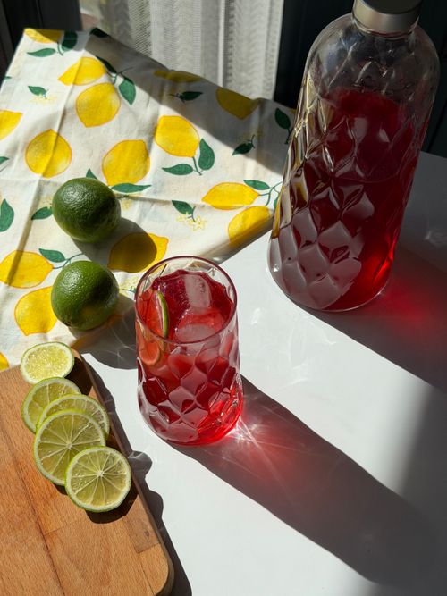 Free A vibrant red drink with a sliced lime under sunlight, perfect for summer refreshment. Stock Photo