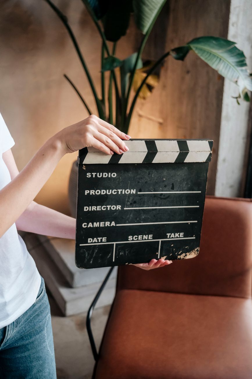 Persoon houdt een leeg filmklapbord binnenshuis, perfect voor filmscènes.