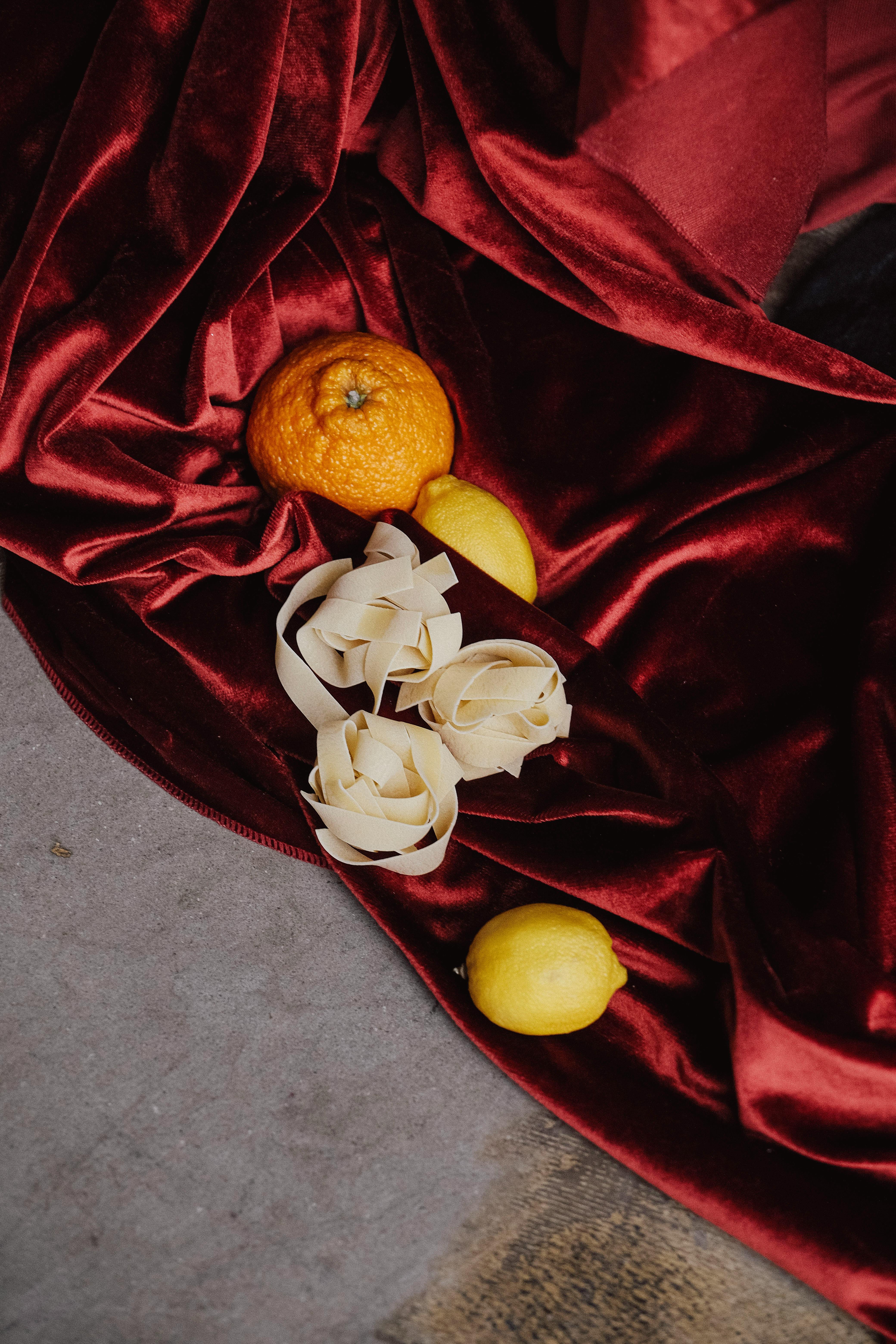 Gratis Lukisan still life elegan yang menampilkan lemon, jeruk, dan bunga di atas beludru merah. Foto Stok