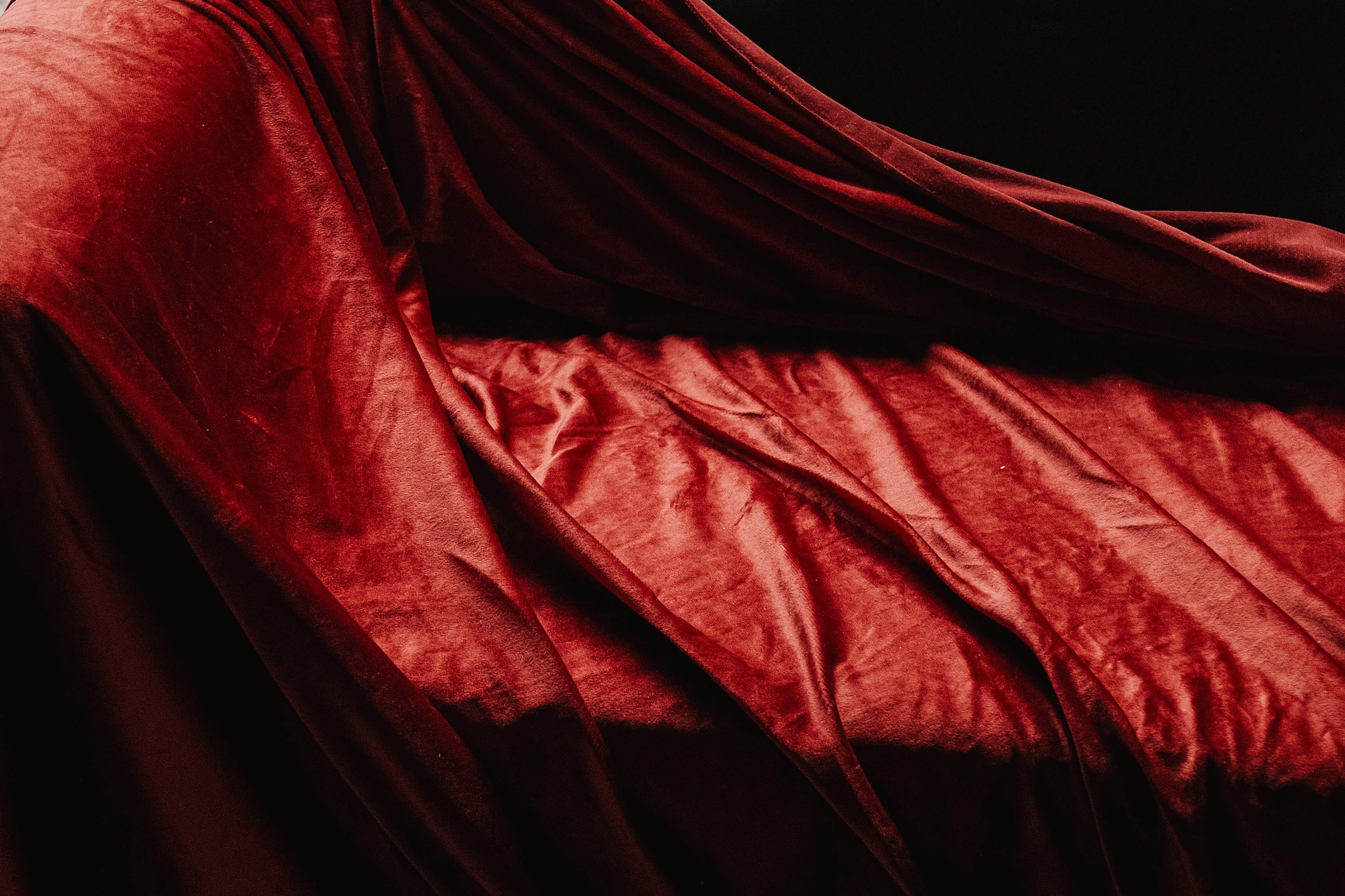 Gratis Tekstur kaya dari kain beludru merah mewah yang terhampar elegan menciptakan bayangan dan sorotan yang lembut. Foto Stok