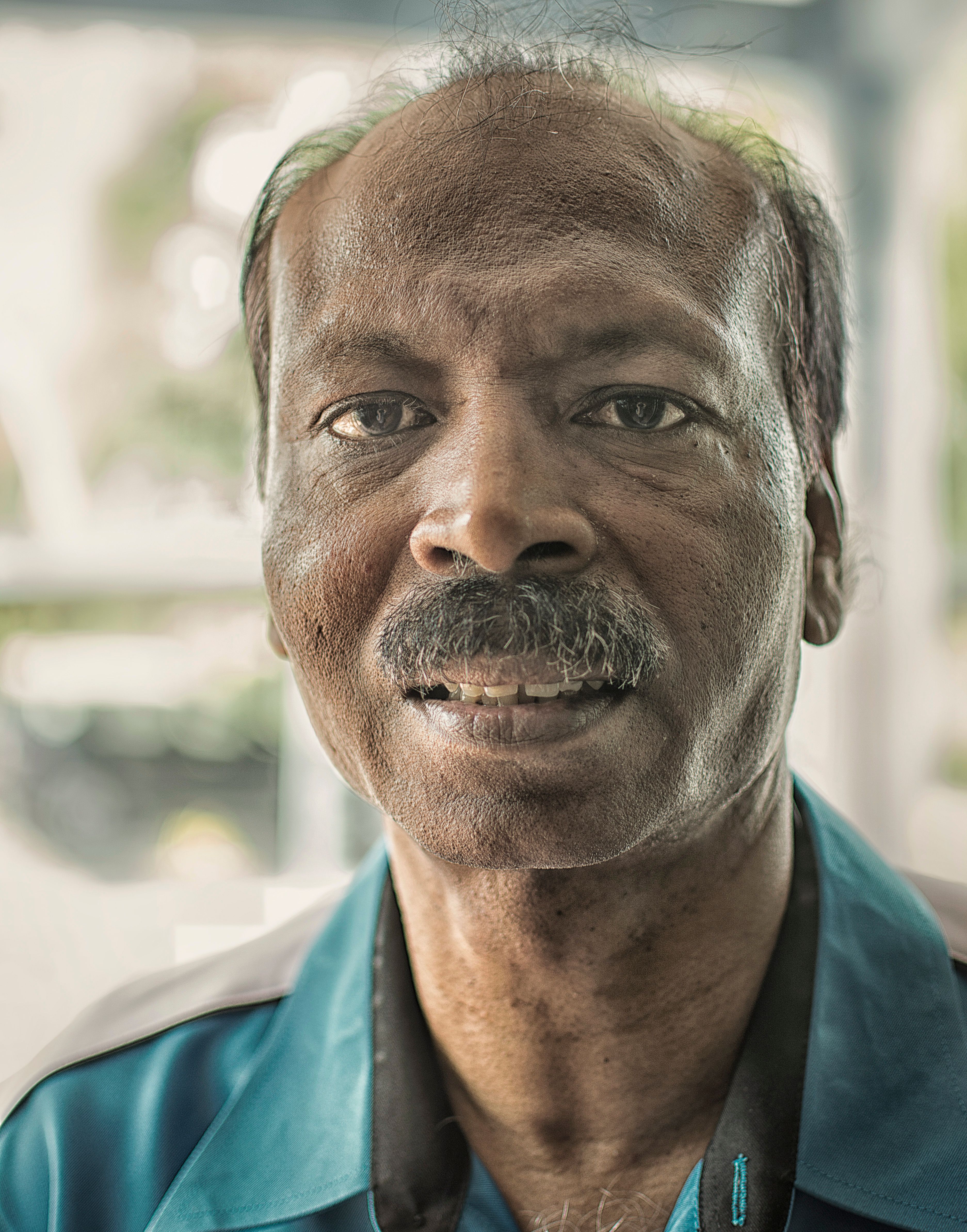 Close-up portrait of an elderly man looking at the camera with a neutral expression.