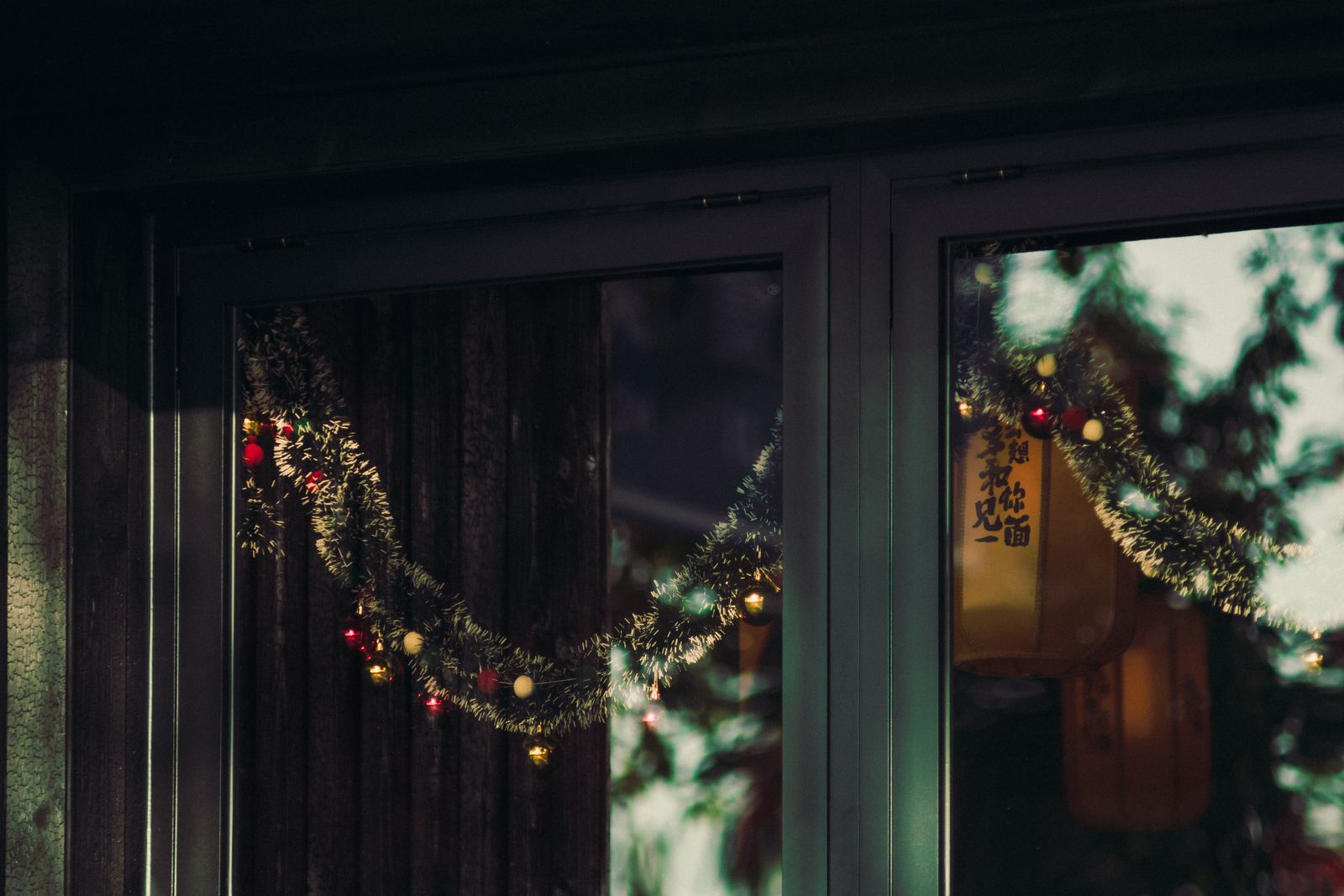 Christmas garland with colorful lights reflecting in a window, capturing holiday warmth.