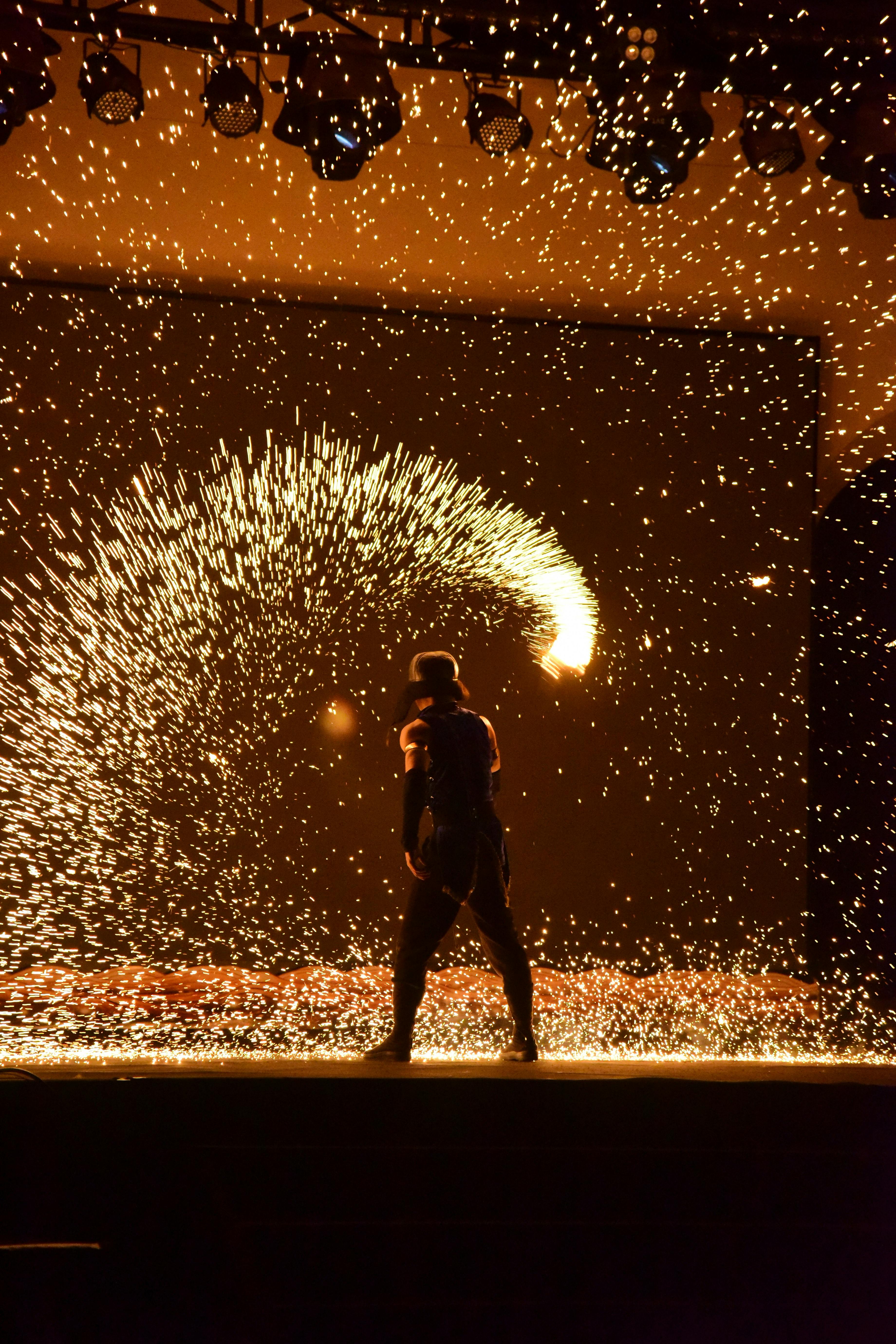 Exciting fire performance with vibrant sparks against a dark background.