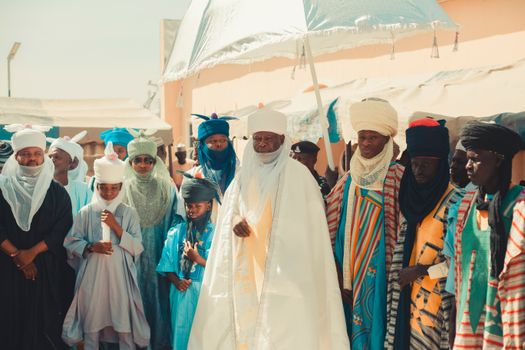 Men and children in vibrant traditional clothing at a cultural festival outdoors.
