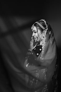 Black and white portrait of a smiling bride in traditional attire.