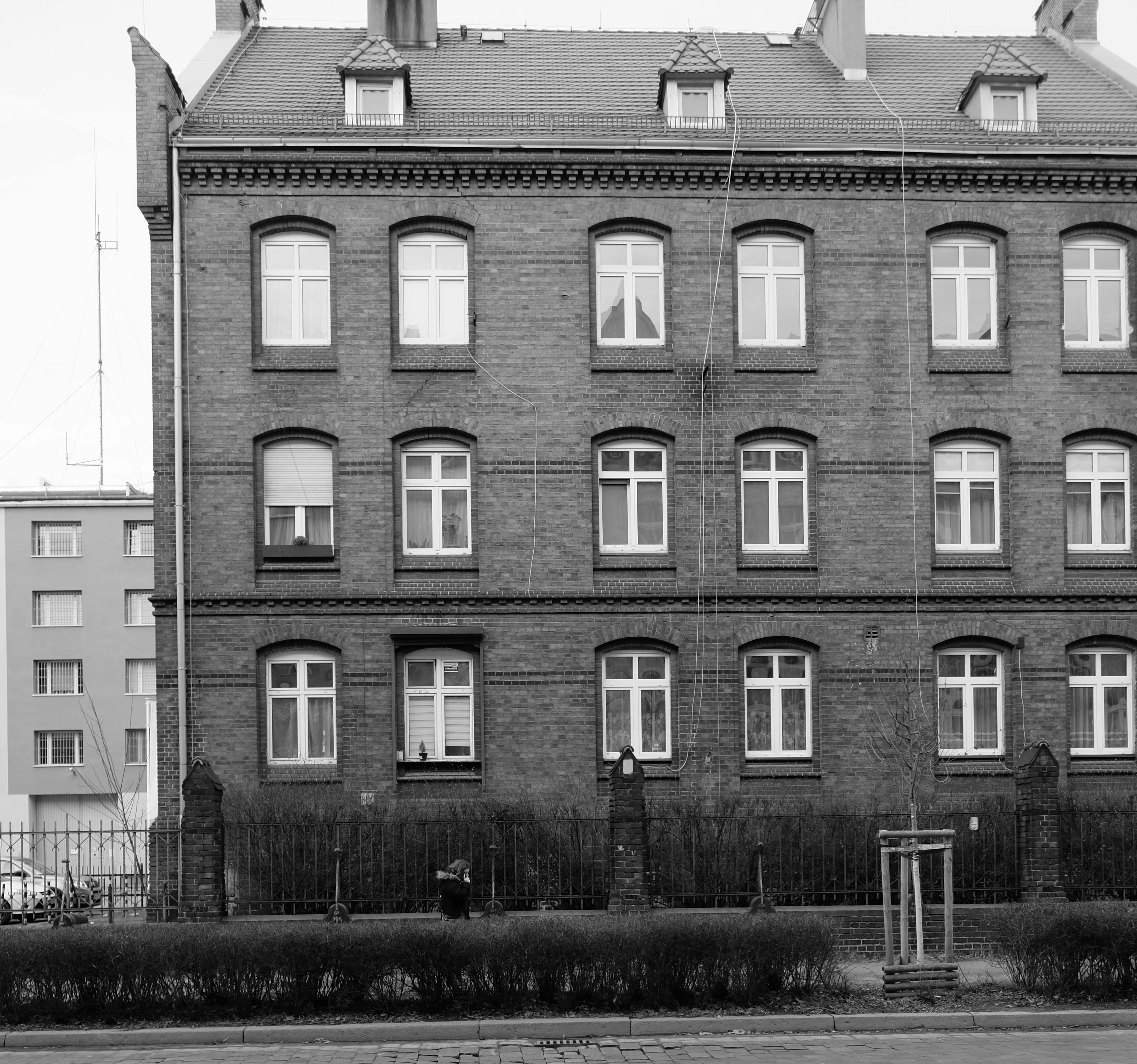 無料 対称的な窓を備えた、古典的な建築美を備えた歴史的なレンガ造りの建物のモノクロ写真。 写真素材