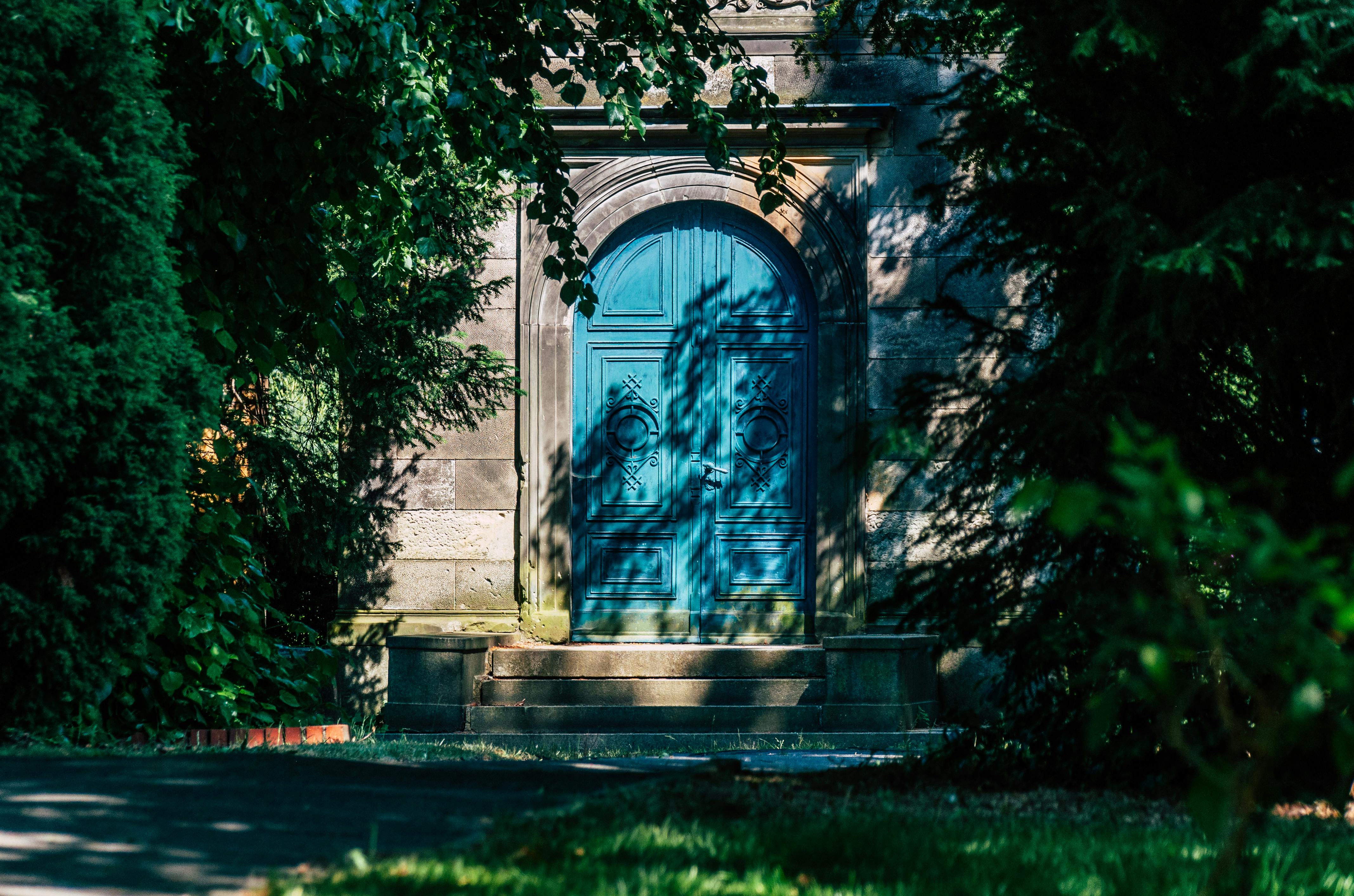 無料 豊かな緑に囲まれた静かな青い扉は、神秘と魅惑を呼び起こします。 写真素材