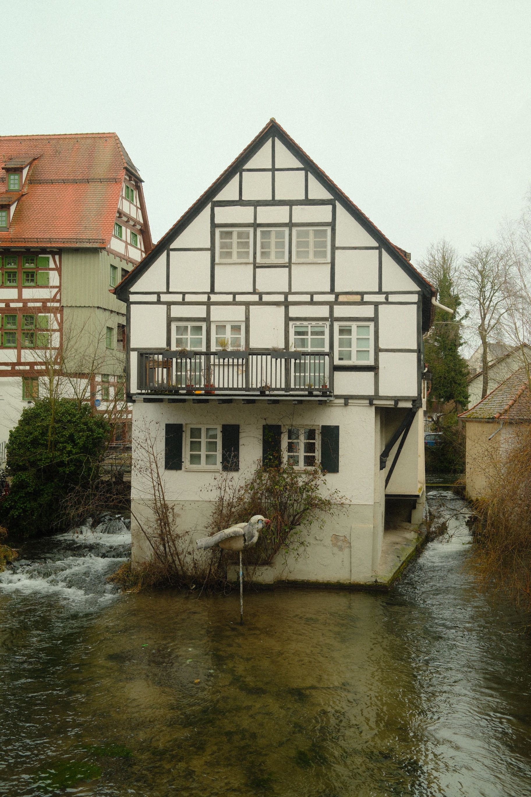 Picturesque half-timbered house on a serene river in Ulm, Germany.