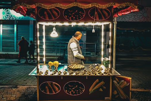 Street vendor selling roasted chestnuts under bright lights on a night street scene.