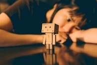 Person Behind Danbo Figurine on Reflective Surface