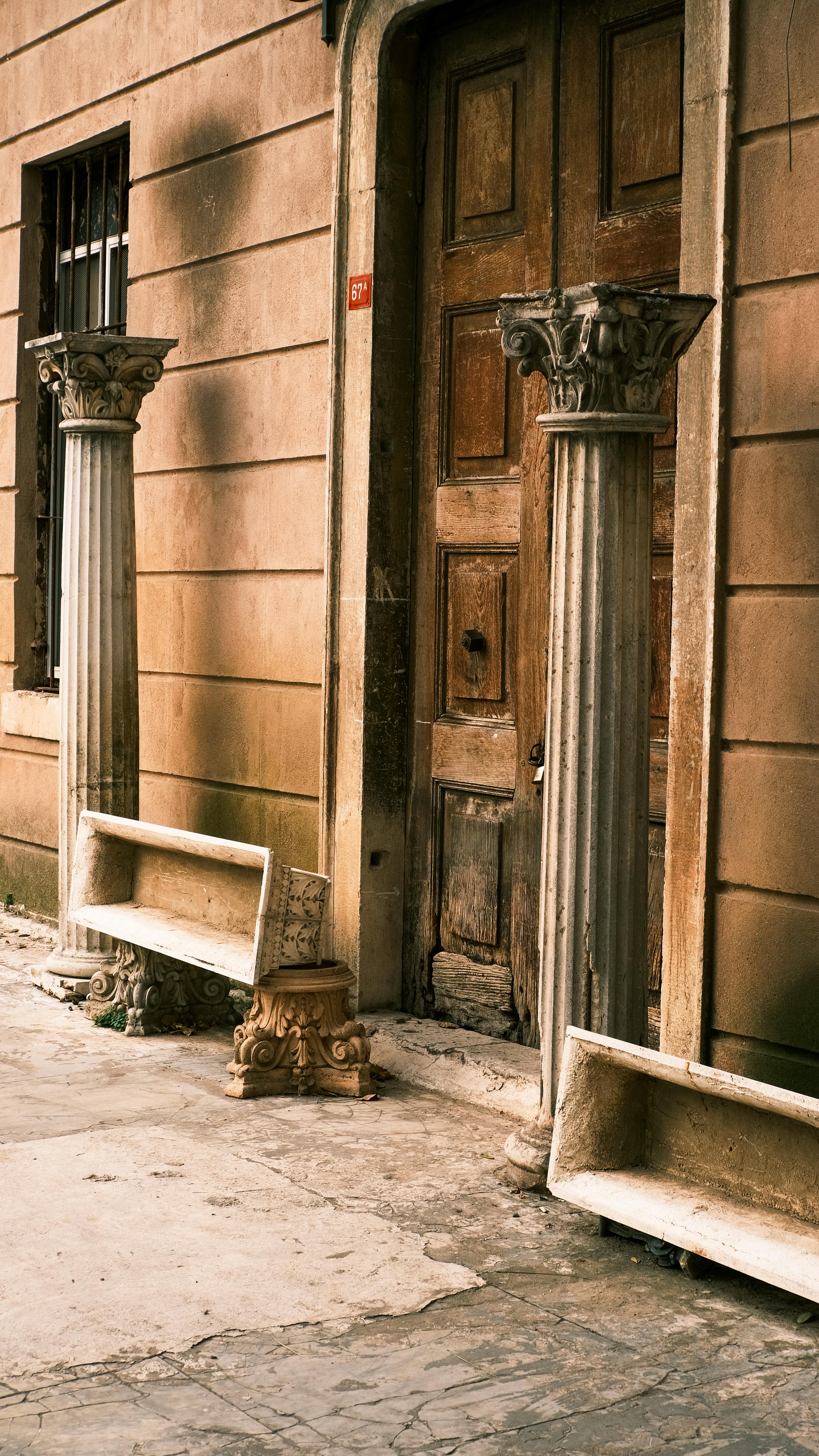 Gratis Rustik døråbning med gamle søjler og bænke i bymæssige omgivelser. Lagerfoto