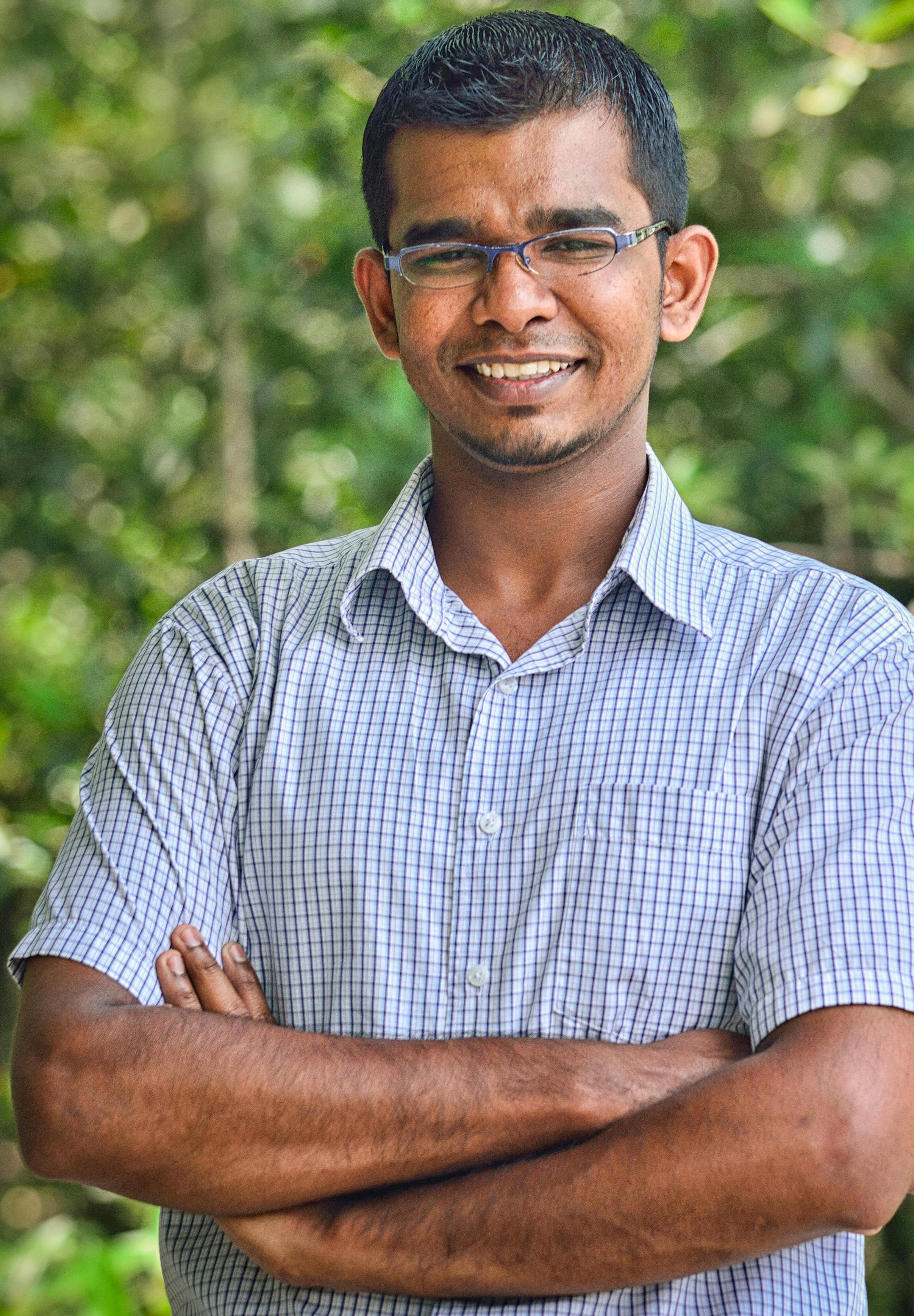 Portrait of a smiling man wearing glasses outdoors in a checked shirt, exuding positivity.