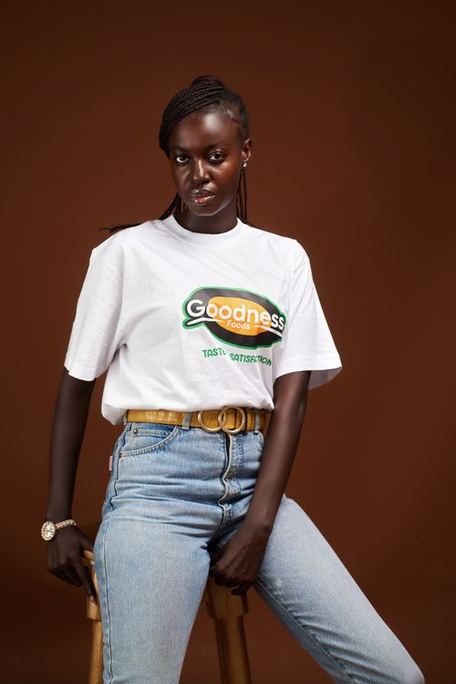 Free Stylish woman in a branded t-shirt and jeans posing confidently against a brown backdrop. Stock Photo
