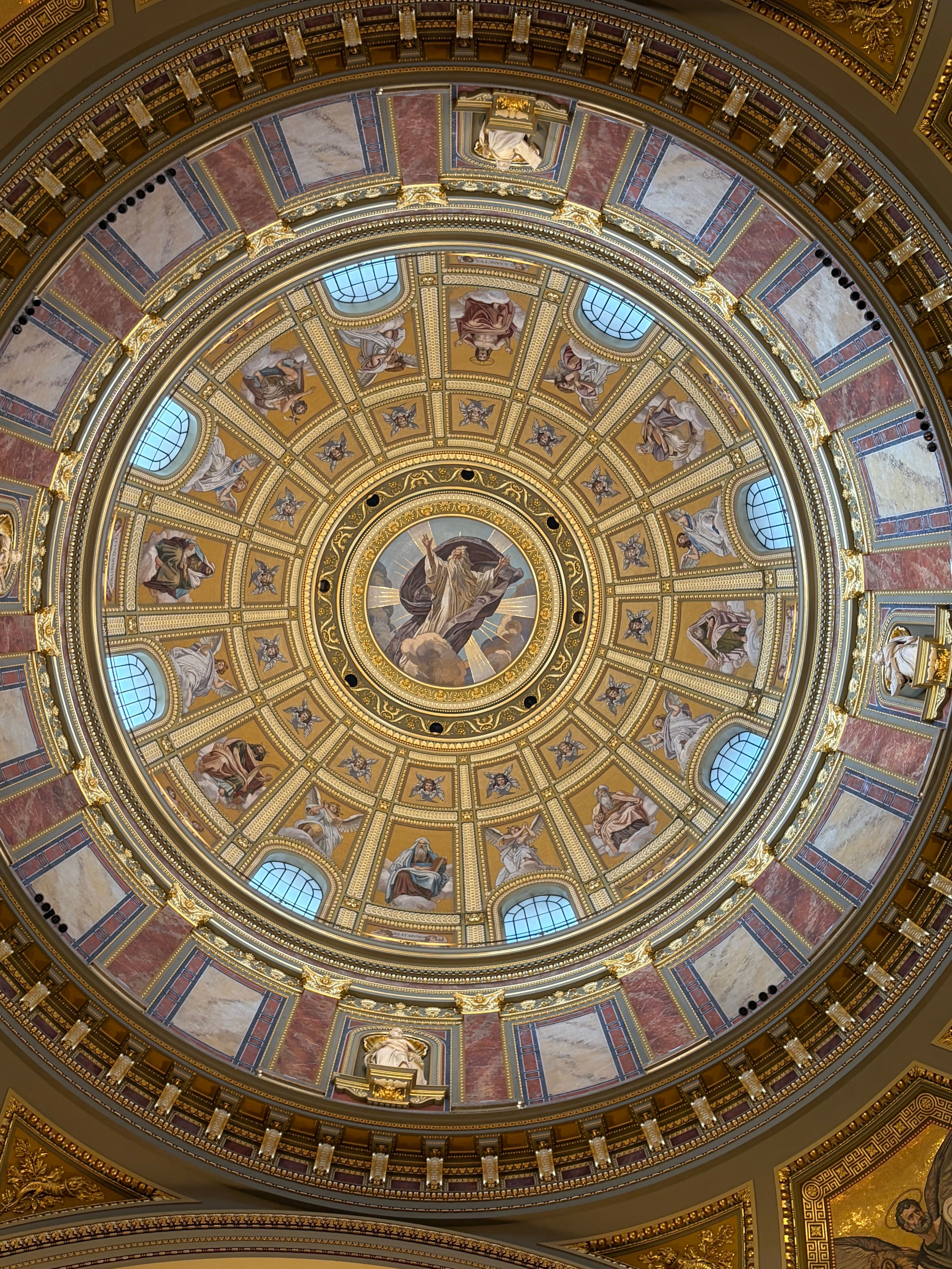 Intricate golden dome ceiling with religious motifs in Budapest, Hungary.