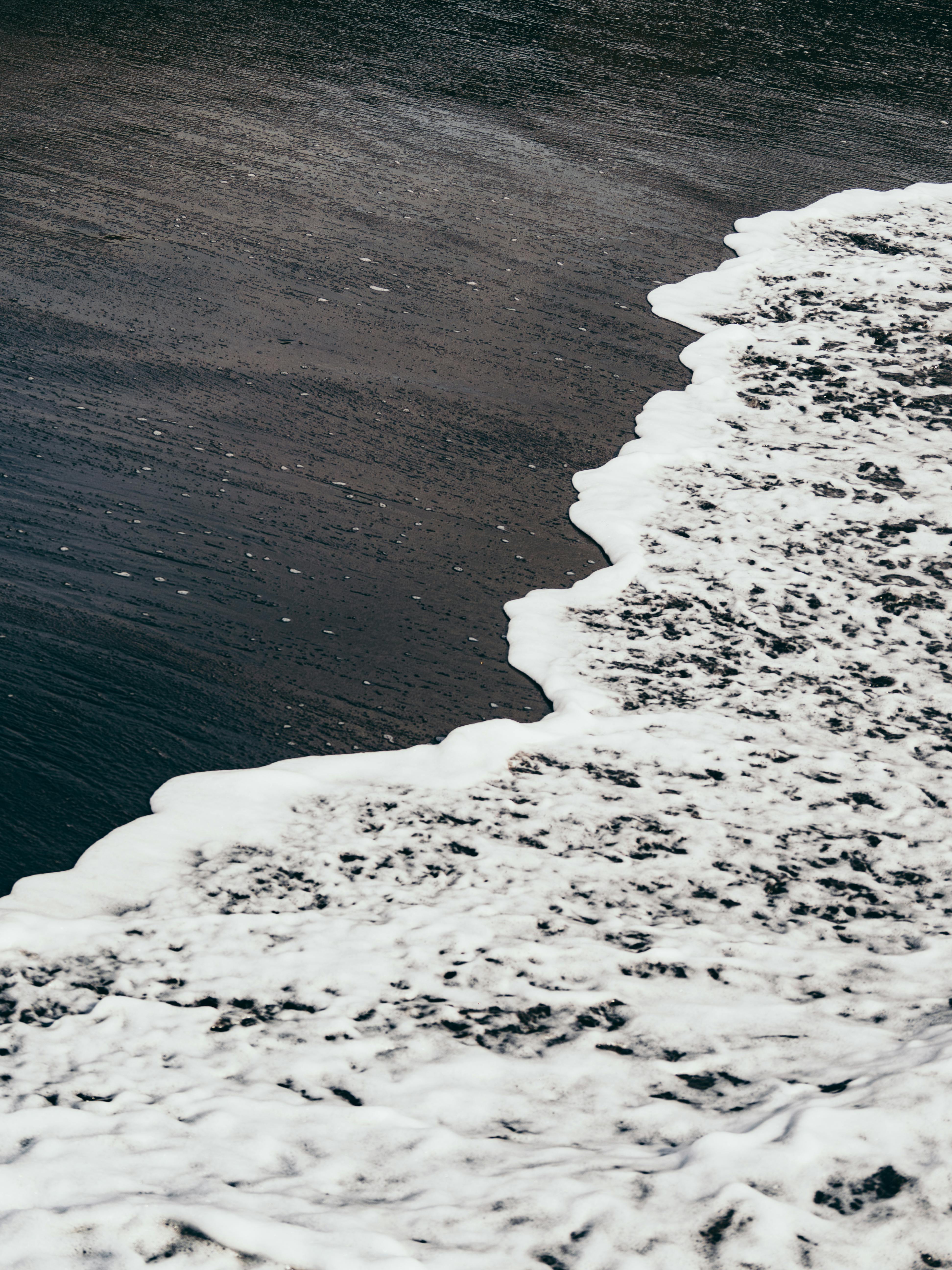 Free Serene view of ocean waves flowing onto a black sand beach, creating a calming contrast. Stock Photo