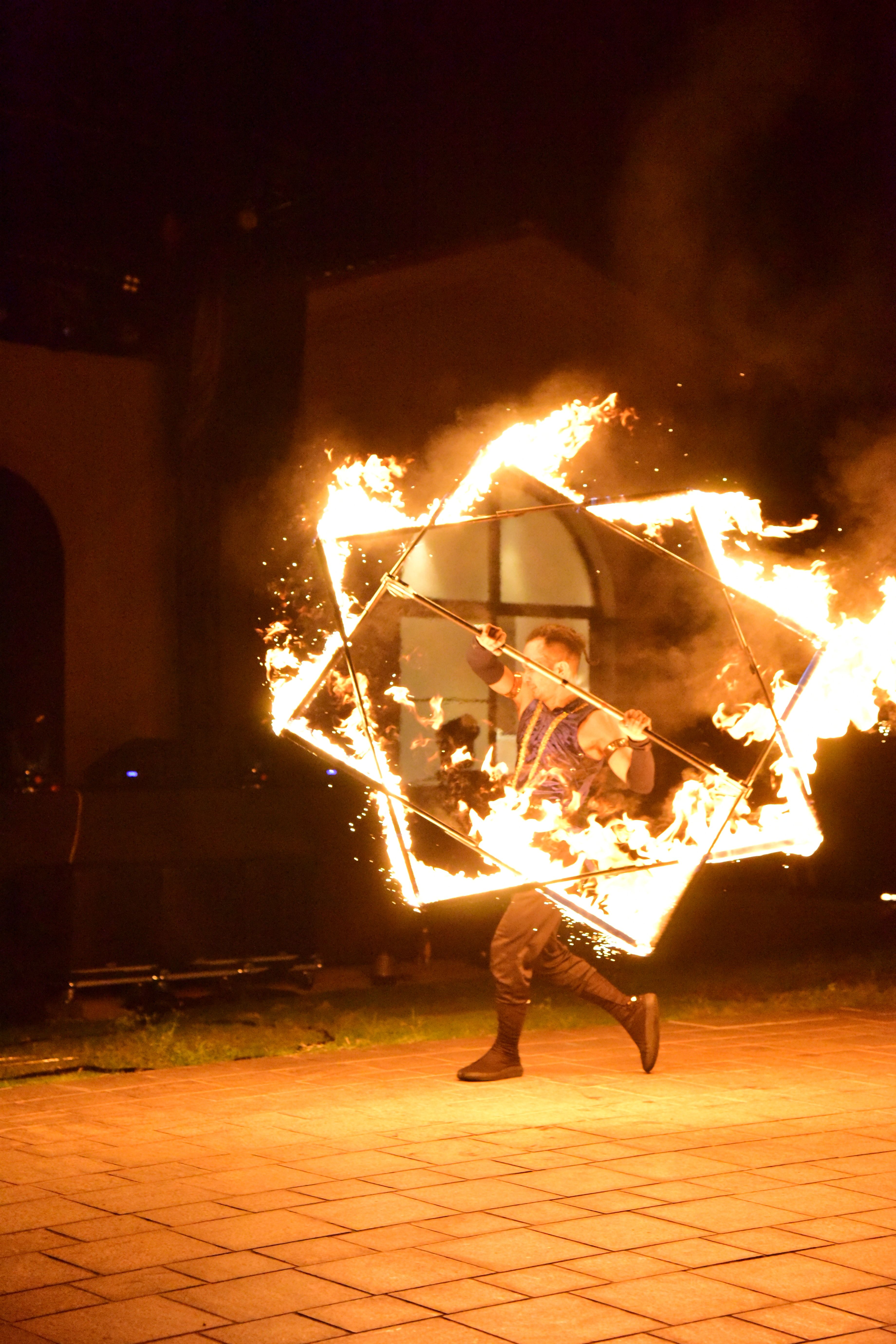 Dramatic fire performance featuring a flaming cube manipulation by a skilled performer at night.