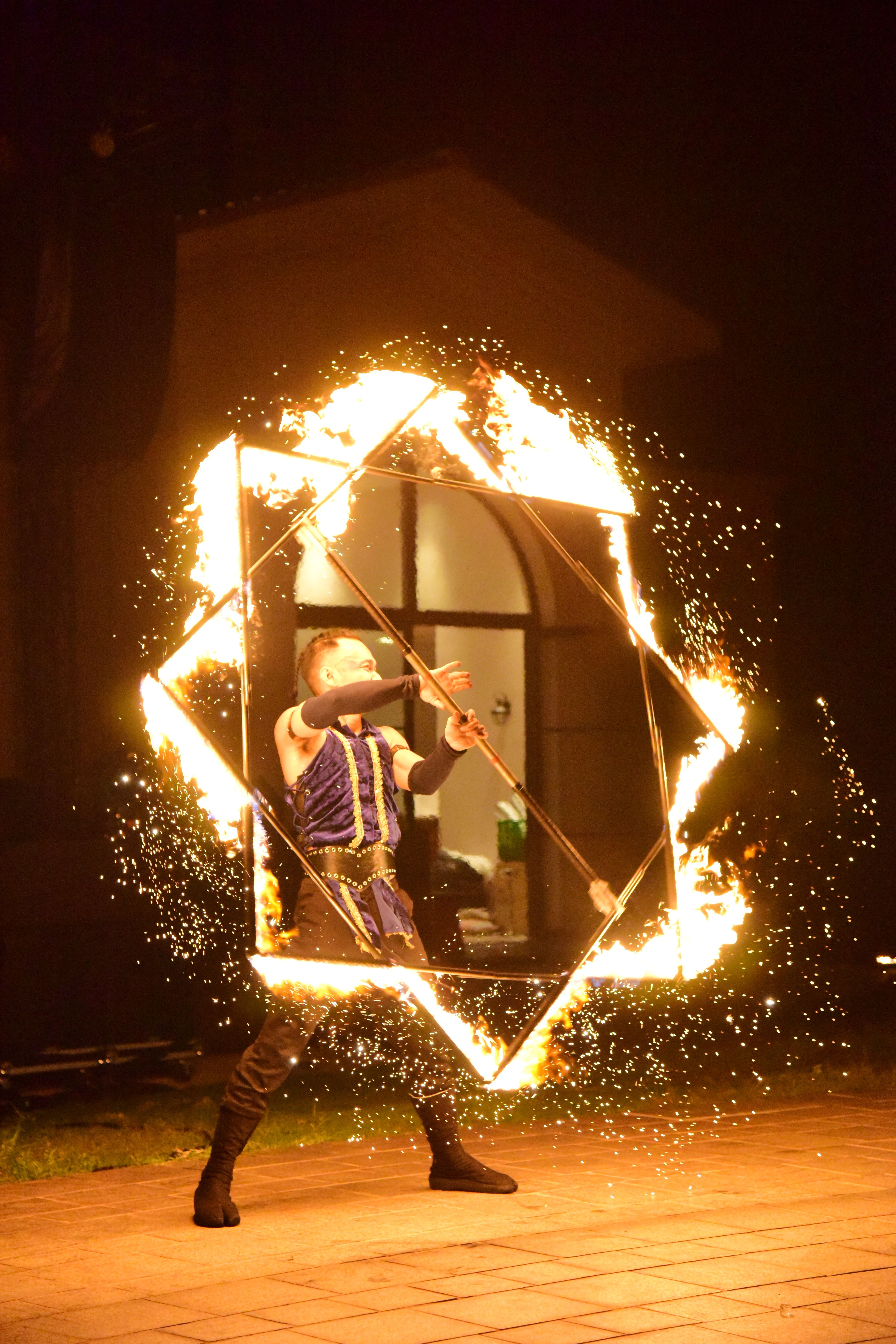 A talented fire performer spinning a fiery cube at night, creating sparks and dramatic visual effects.