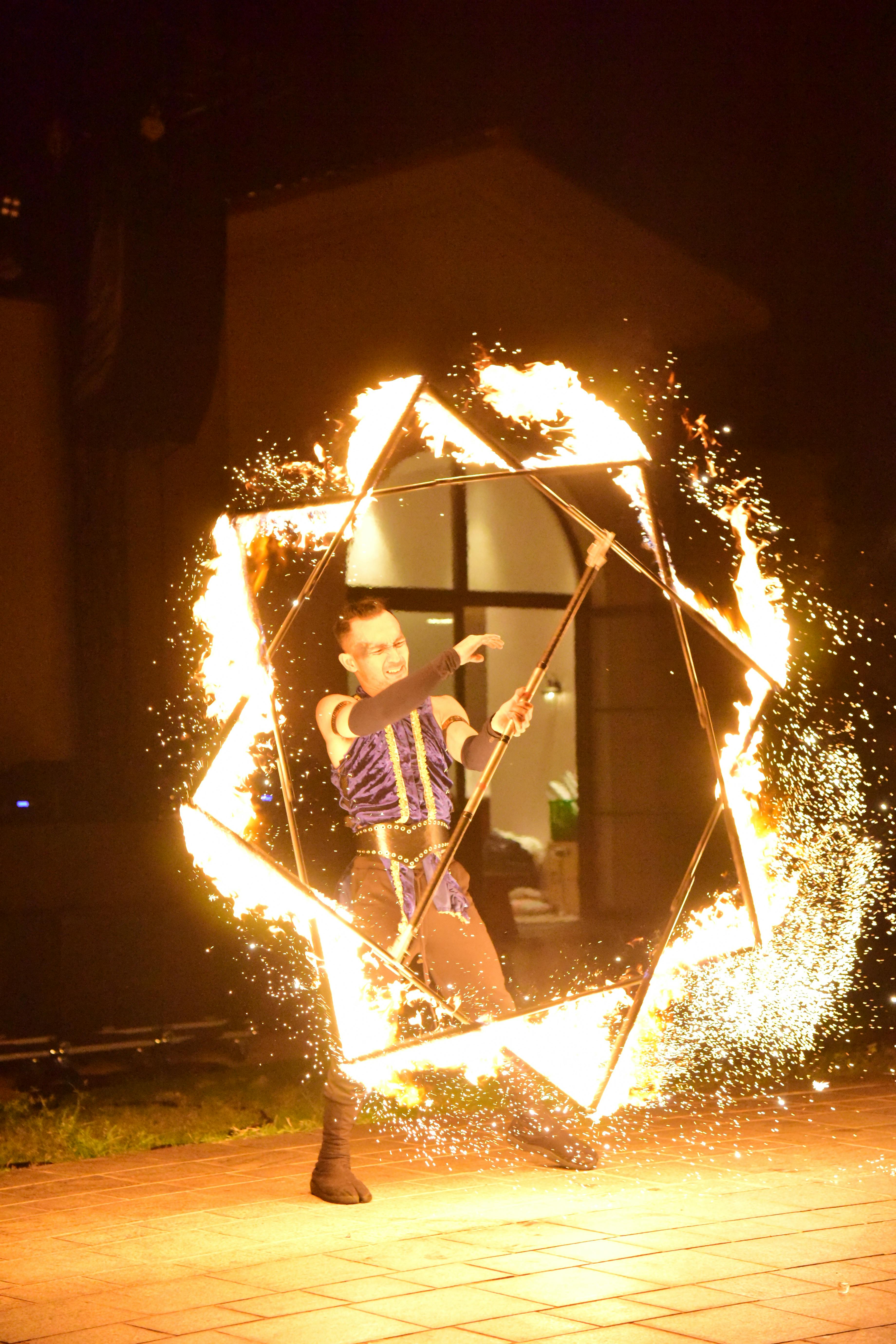 Gratis Pertunjukan api malam hari yang mendebarkan dengan properti geometris dan percikan api, menampilkan keterampilan dan seni. Foto Stok