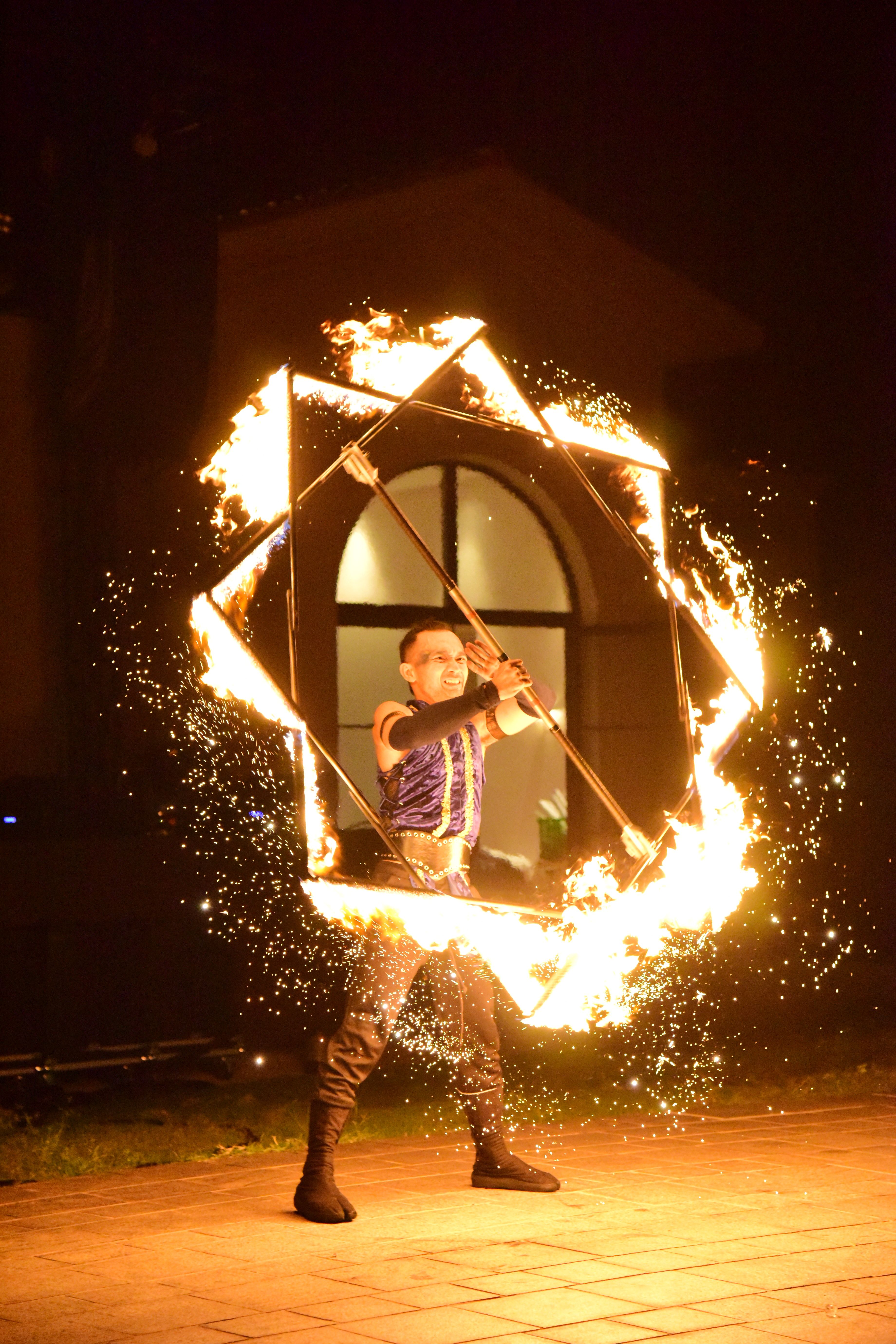 A mesmerizing fire dancer performing with flames in an outdoor night setting.