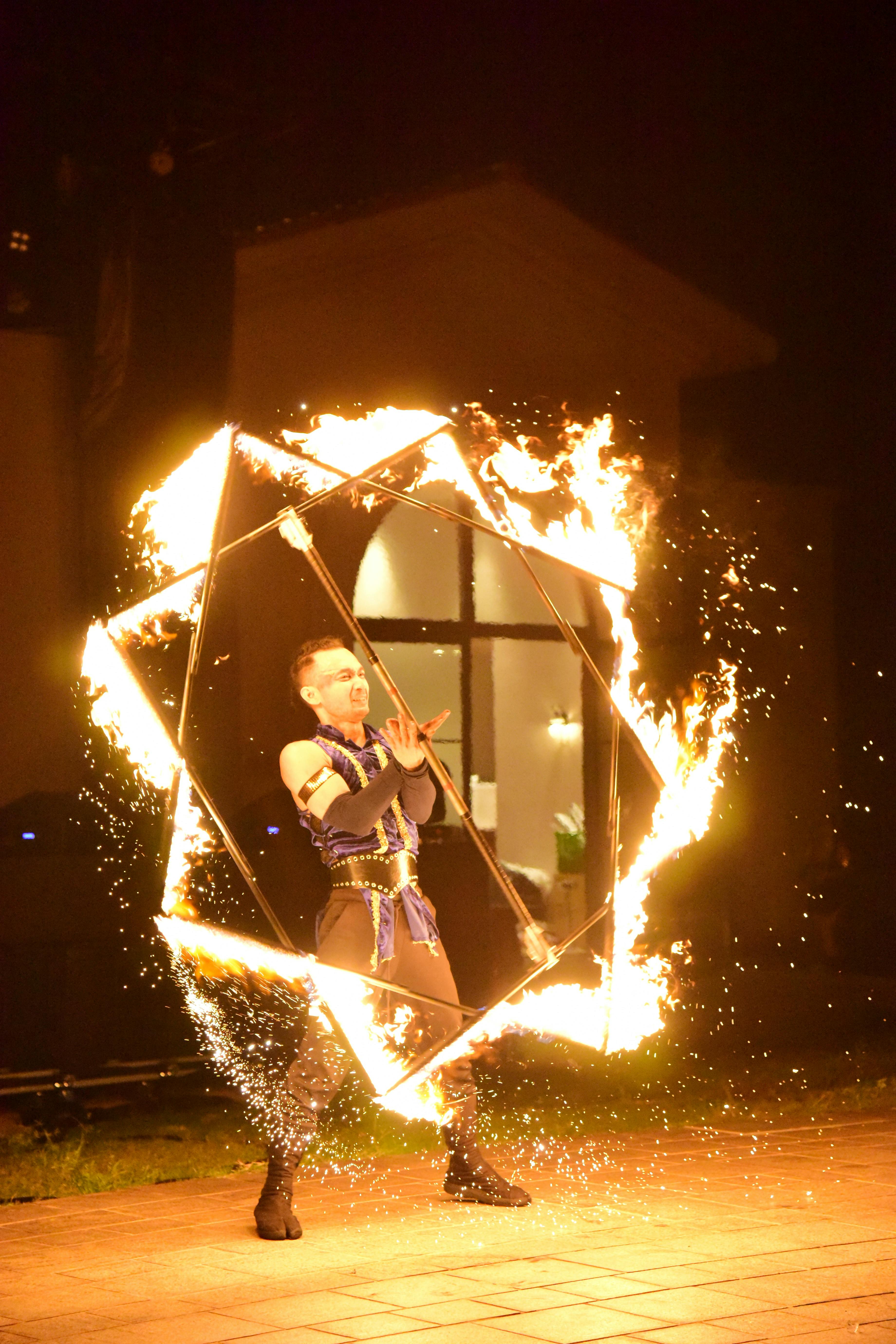 Fire performer dazzling with intricate movements at night. Captivating display of skill, flames, and artistry.